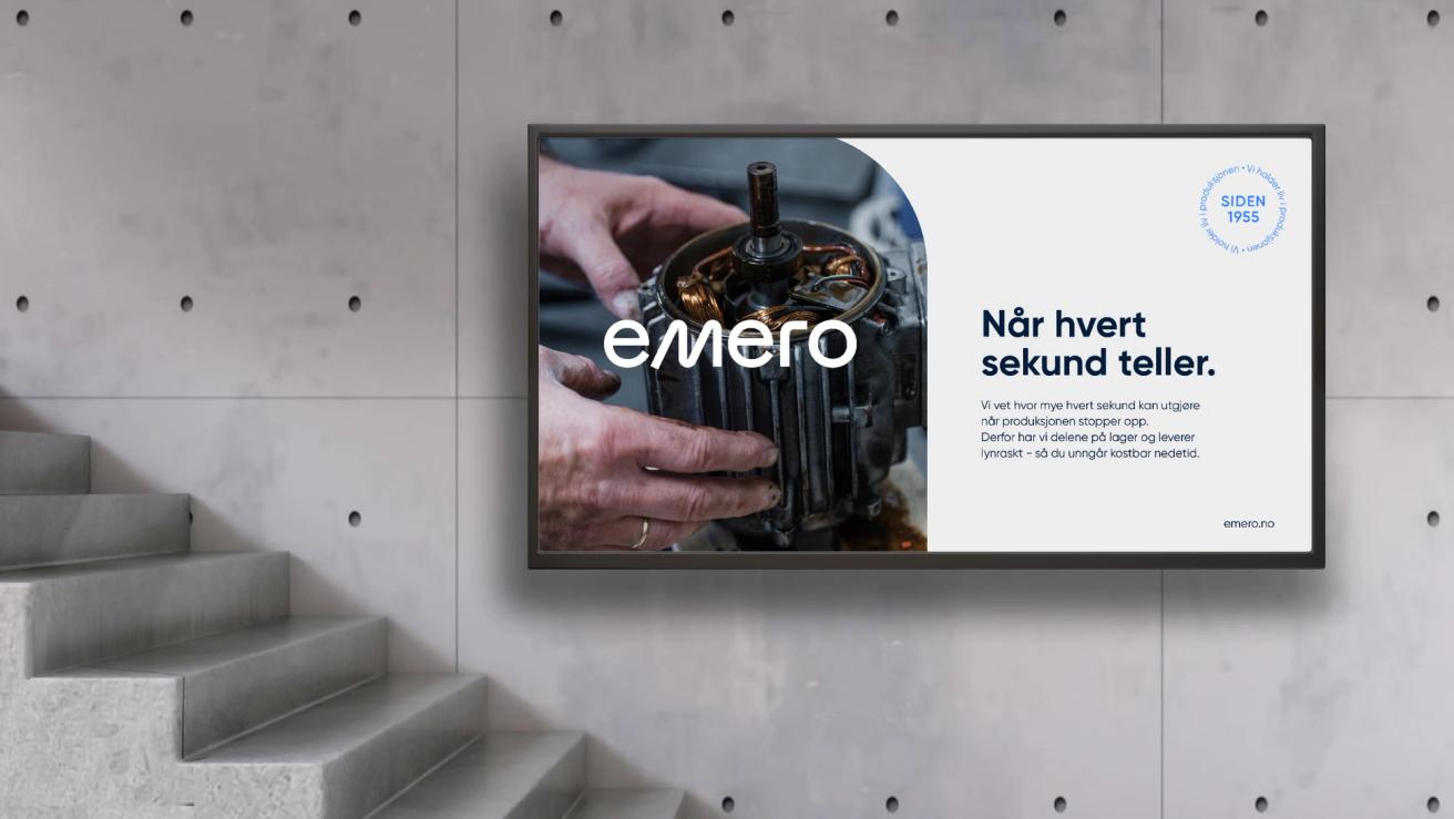 A wall-mounted digital display showing Emero branding with hands repairing an electric motor and Norwegian text — by Nonspace