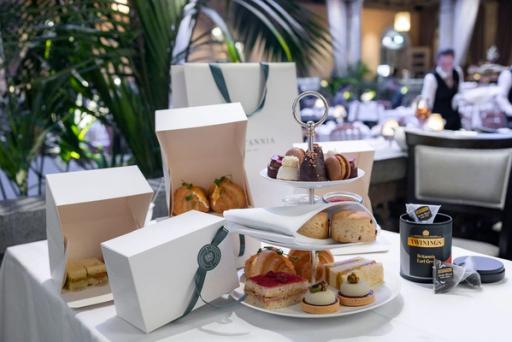 Et afternoon tea-oppsett med etasjefat, bakstvarer, Twinings-te og elegante gavebokser på et hvitdekket bord — av Nonspace