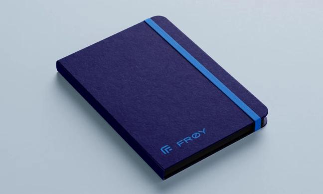 A dark blue hardcover notebook with FRØY branding and a light blue elastic closure band — by Nonspace