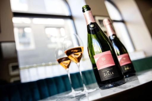 To glass roséchampagne og en flaske Ayala Rosé Majeur på en marmorbenk ved et vindu — av Nonspace