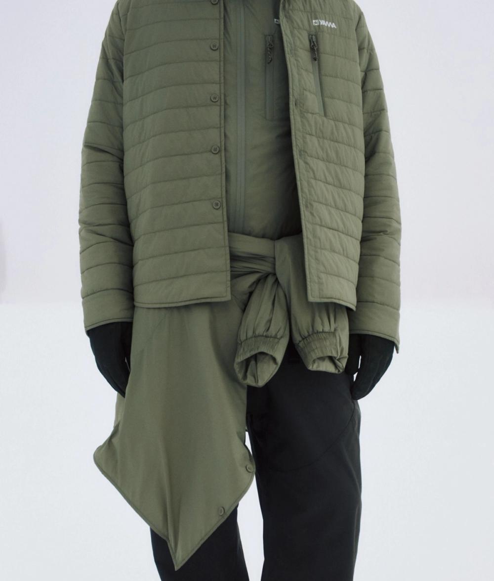 A person wearing a quilted olive green jacket with a matching shirt tied at the waist and black pants — by Nonspace