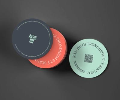 Stacked circular coasters in navy, coral, and mint green featuring QR codes and Norwegian text for Trondheim — by Nonspace