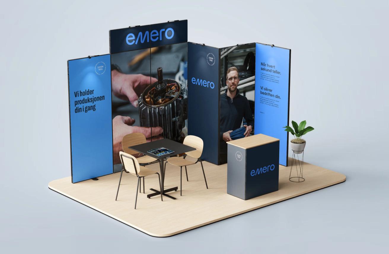 A trade show booth for Emero featuring blue branded panels, a meeting table with chairs, and a reception counter — by Nonspace