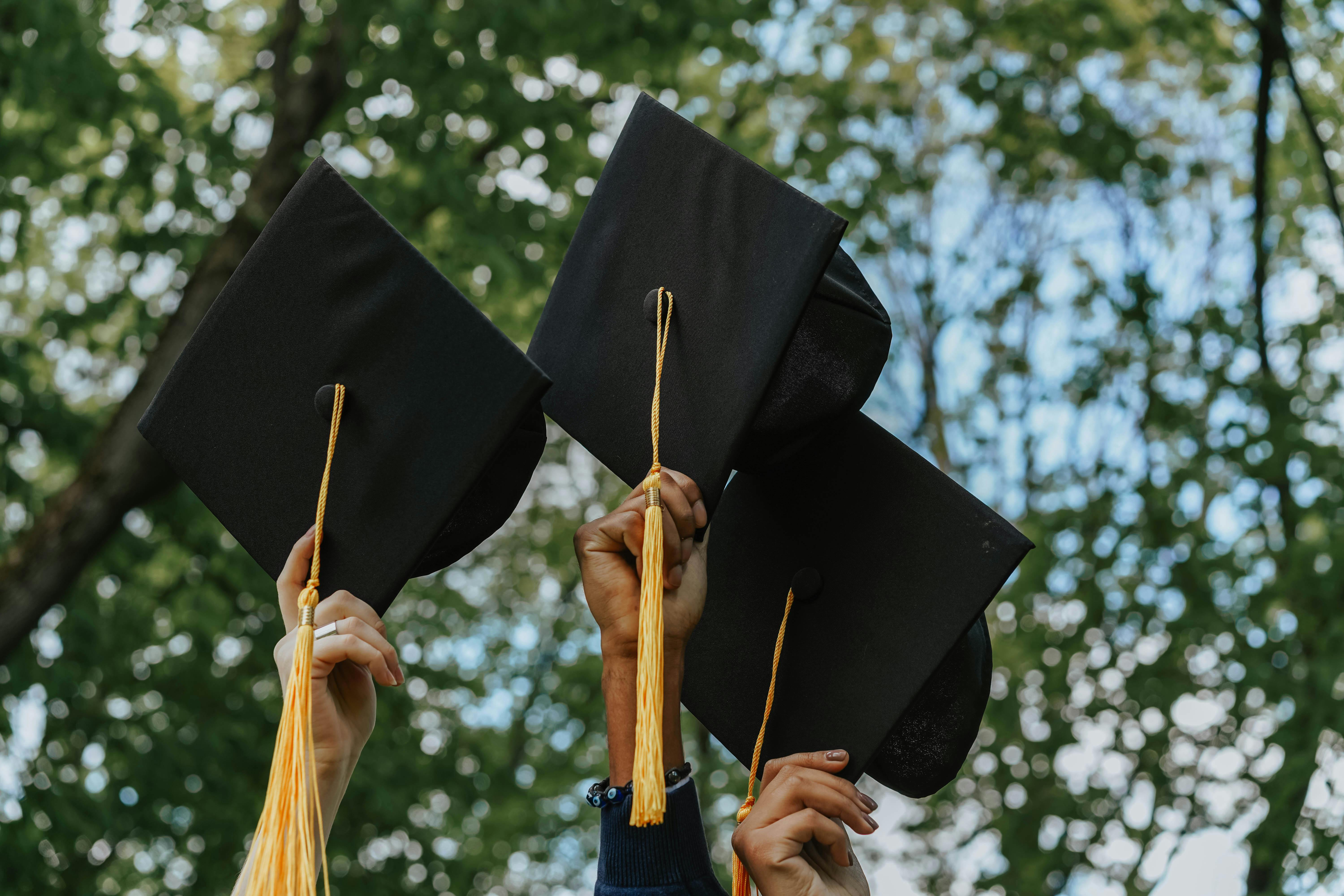 Graduates holding caps in the air, representing how NJ expungement can help people with criminal records move forward after graduation.