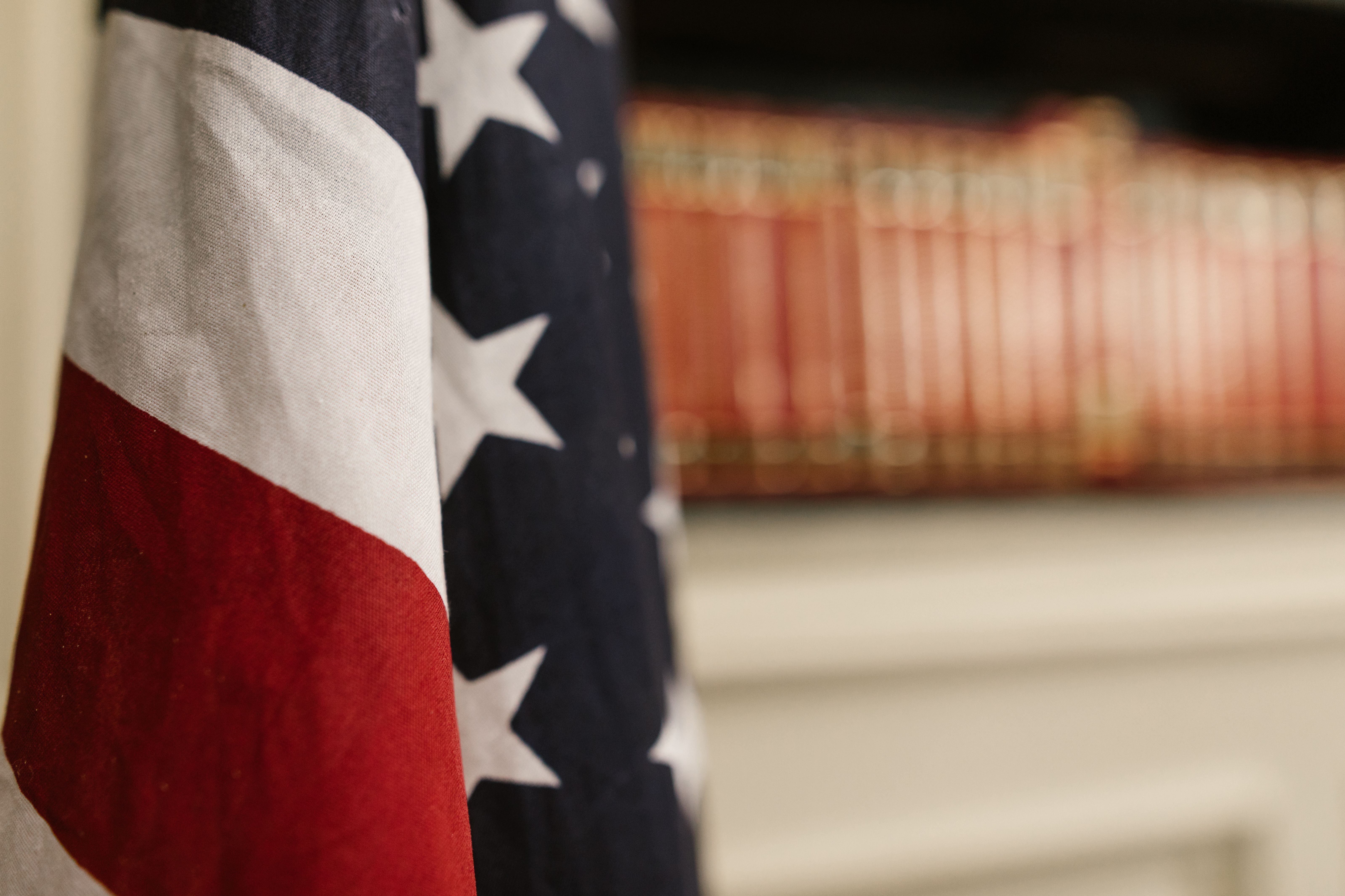 Close-up of an American flag draped beside a shelf of red law books, representing military justice and Article 120 expungement cases in New Jersey.