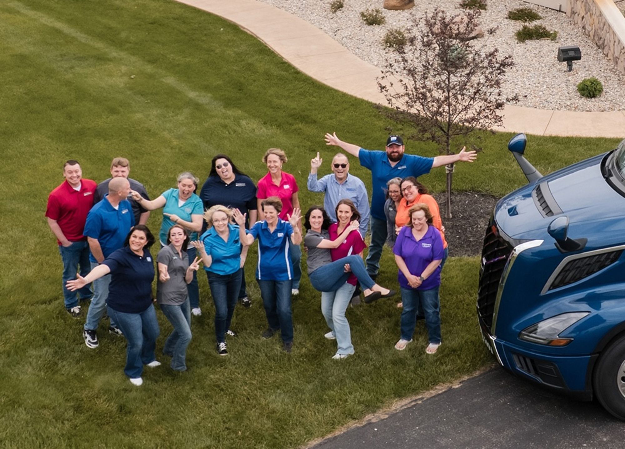 Dick Lavy Trucking office team waving next to a Volvo tractor on the Bradford, Ohio lawn