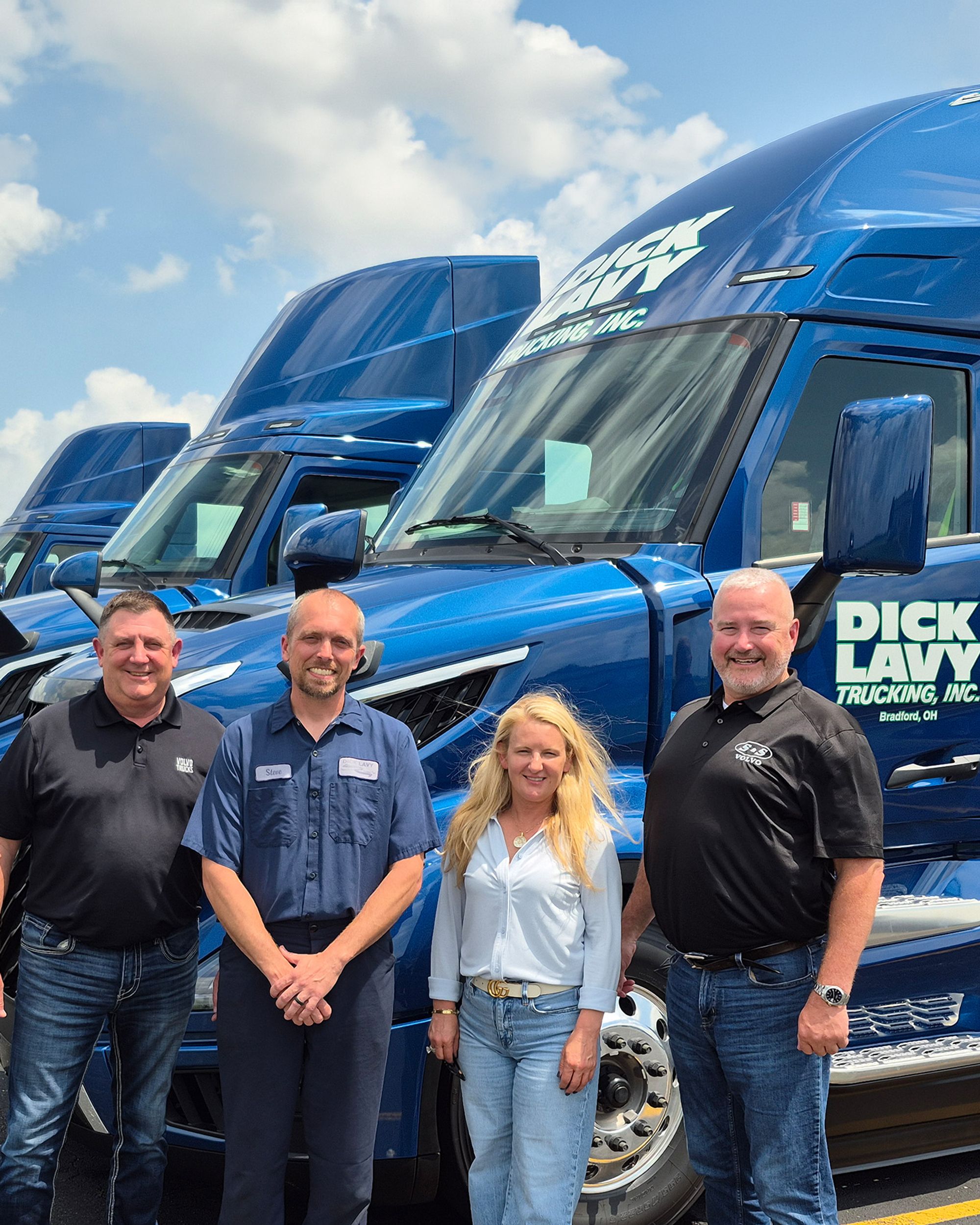 Dick Lavy Trucking team standing in front of a row of new Volvo tractors in Bradford, Ohio