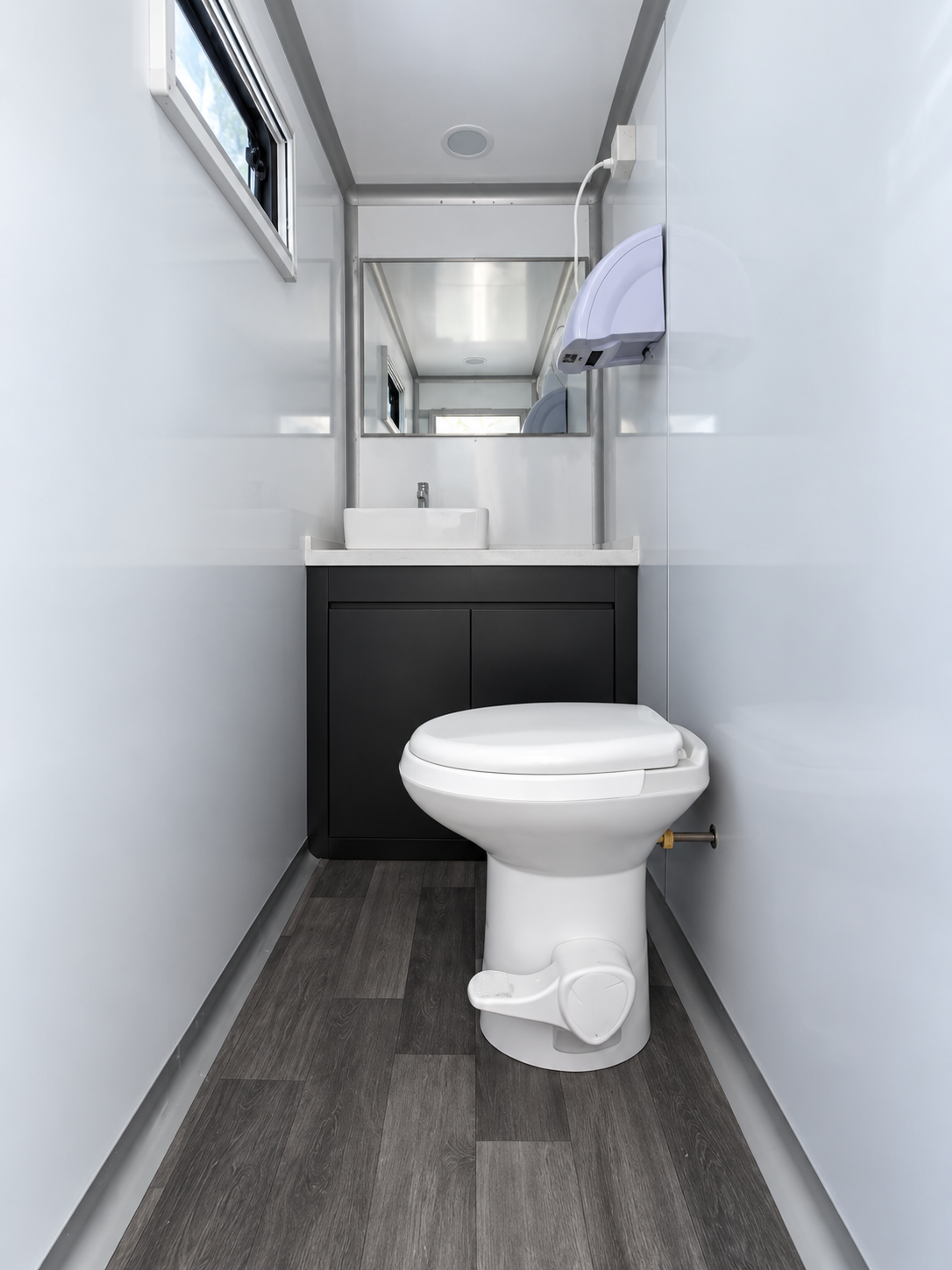Restroom stall interior with toilet, vanity sink, mirror and hand dryer