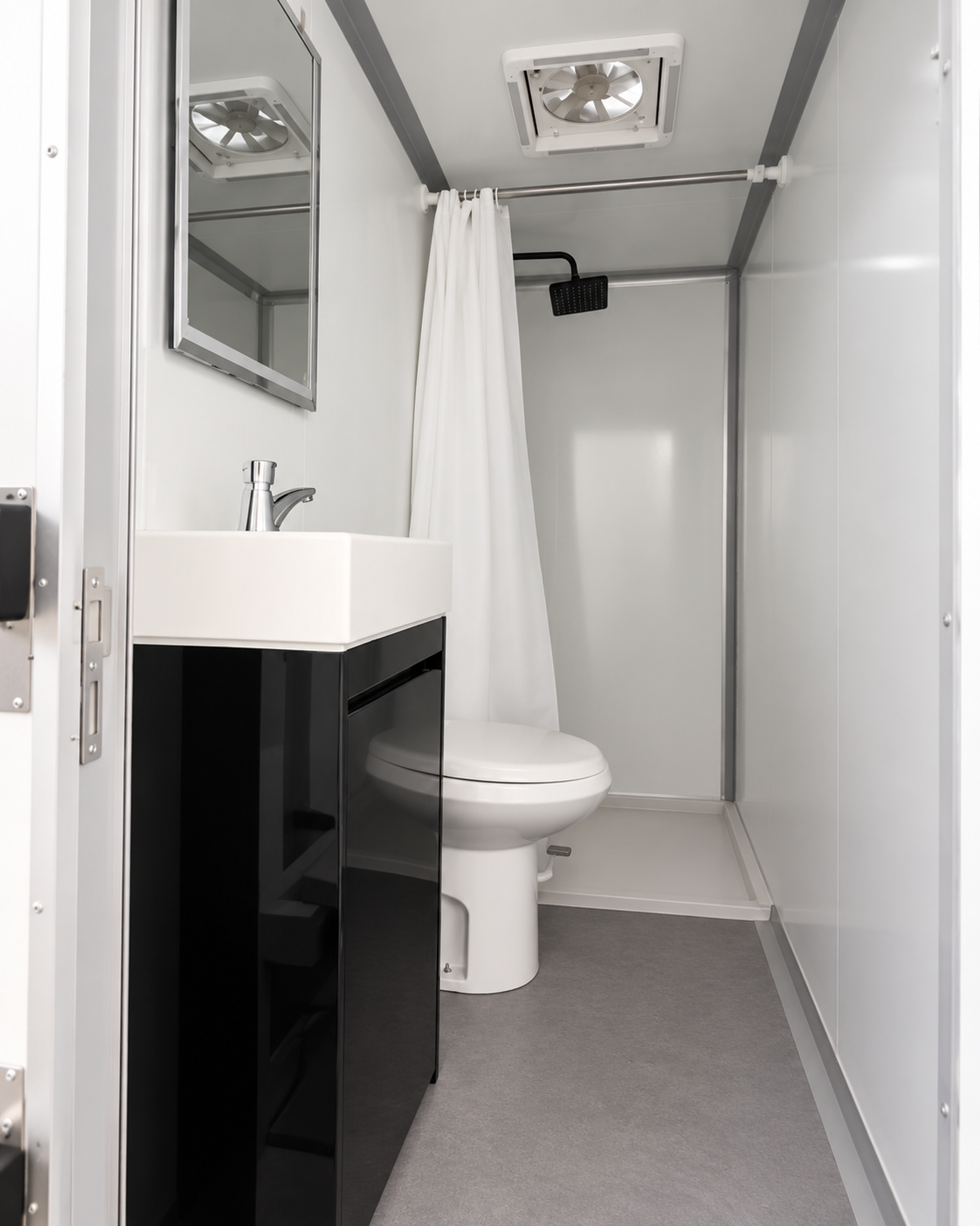 Standard stall interior with in-stall shower, toilet, vanity sink and roof vent