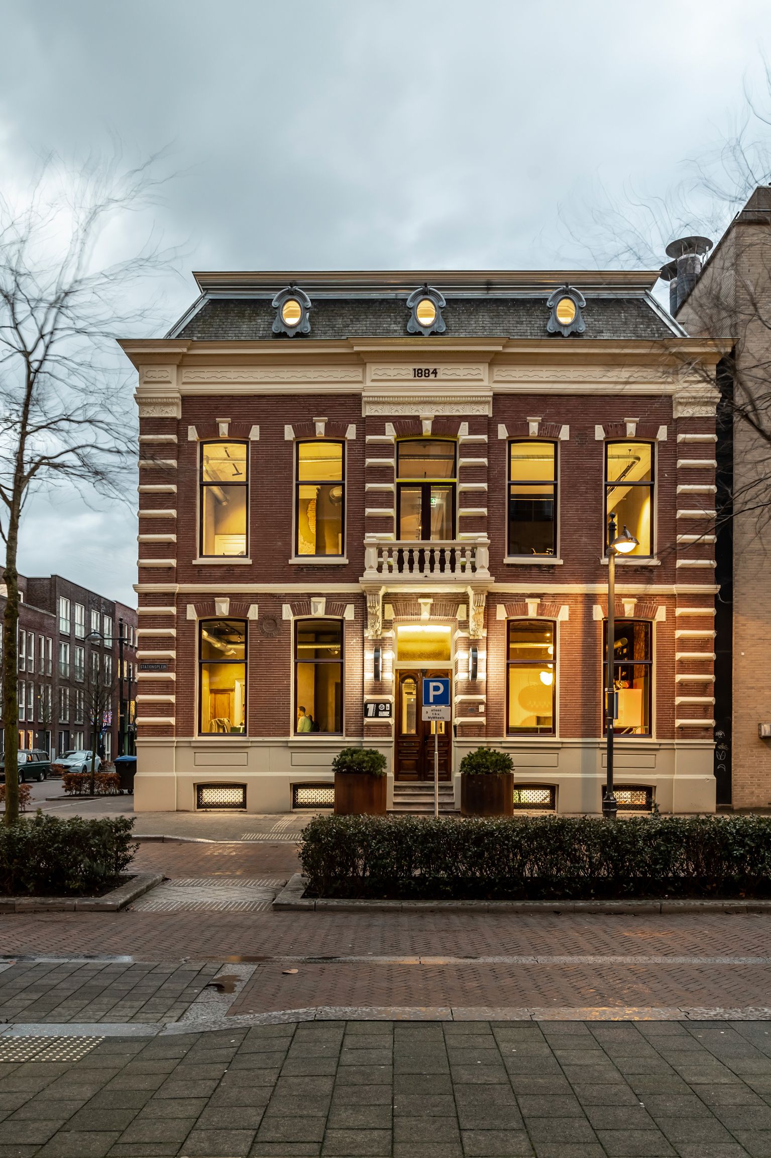 Historic office building of An Apple A Day in Breda at dusk, located on a corner near the central station, with illuminated windows revealing the atmosphere inside the agency.