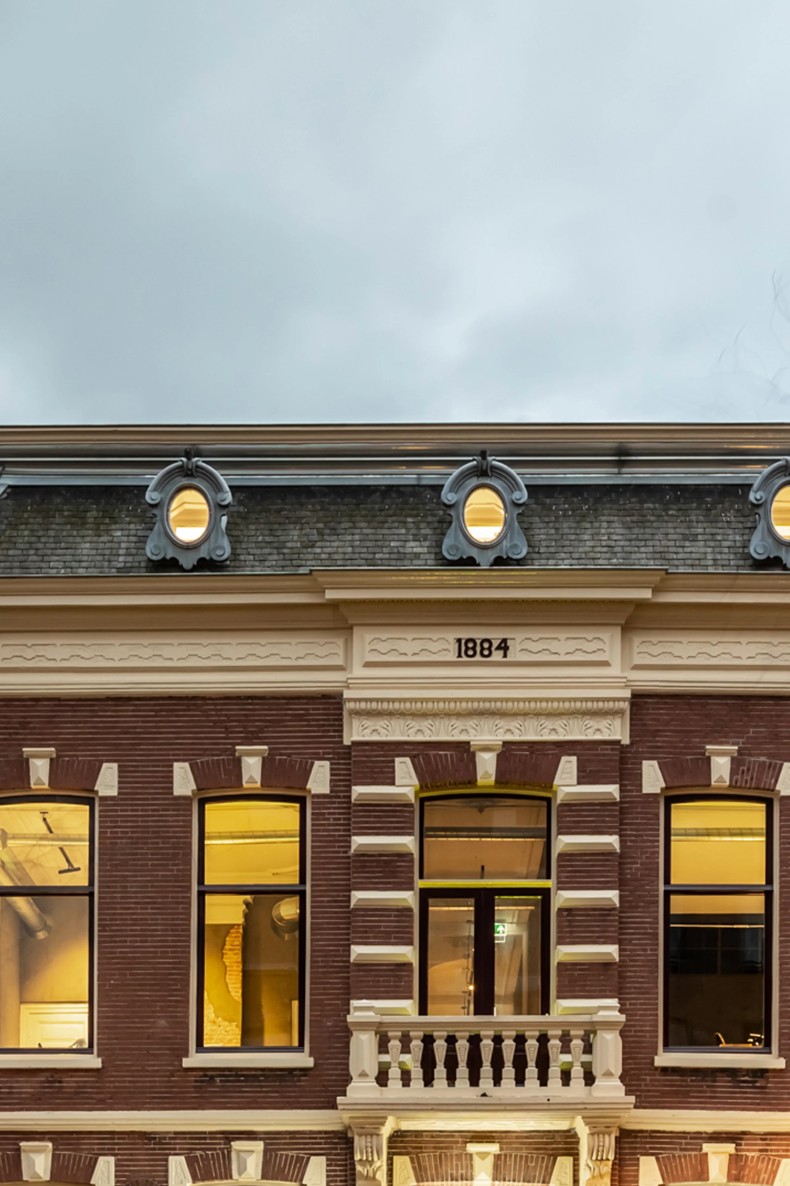 Historic office building of An Apple A Day in Breda at dusk, located on a corner near the central station, with illuminated windows revealing the atmosphere inside the agency.