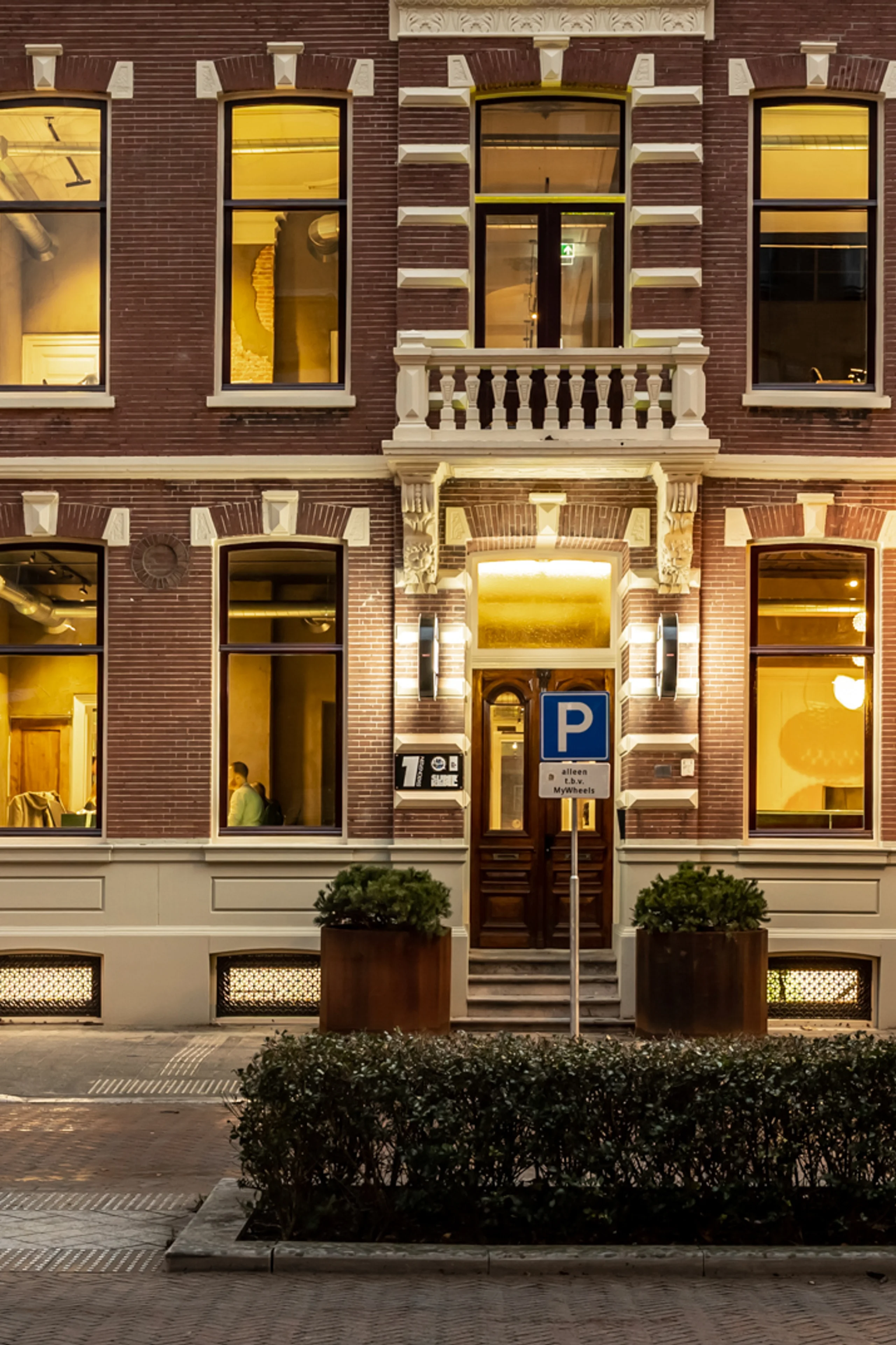 Historic office building of An Apple A Day in Breda at dusk, located on a corner near the central station, with illuminated windows revealing the atmosphere inside the agency.