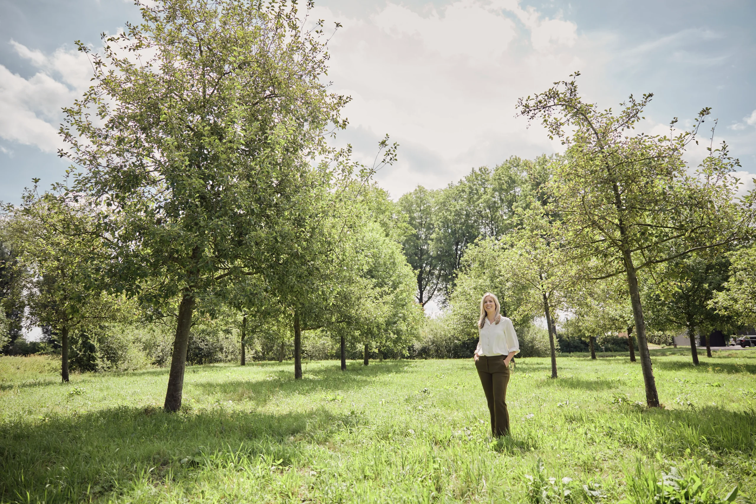 lack-and-white photo of a woman standing among trees in an orchard, symbolizing An Apple A Day's brand philosophy that a strong brand grows like an apple tree.