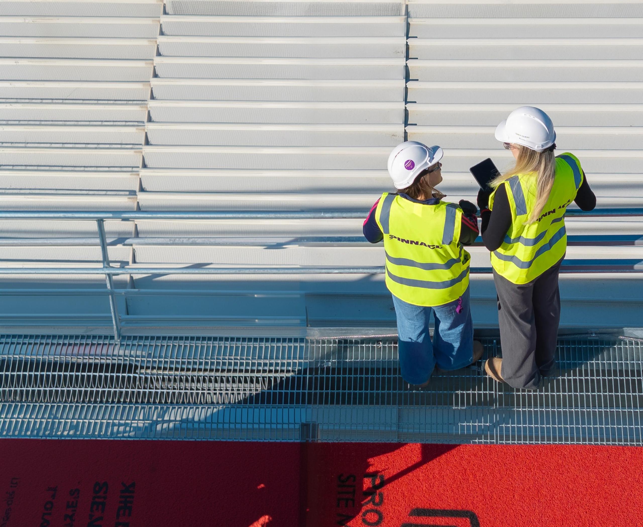 Two Pinnacl team members in hi-vis reviewing a tablet on site