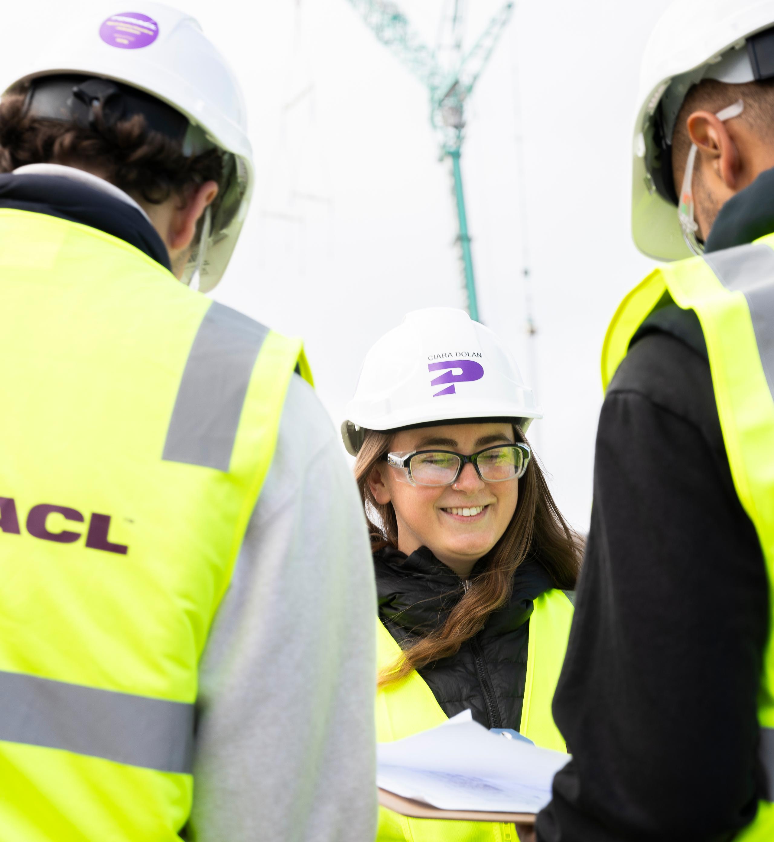 Pinnacl team members in branded hi-vis vests gathered outdoors, a smiling woman at the centre