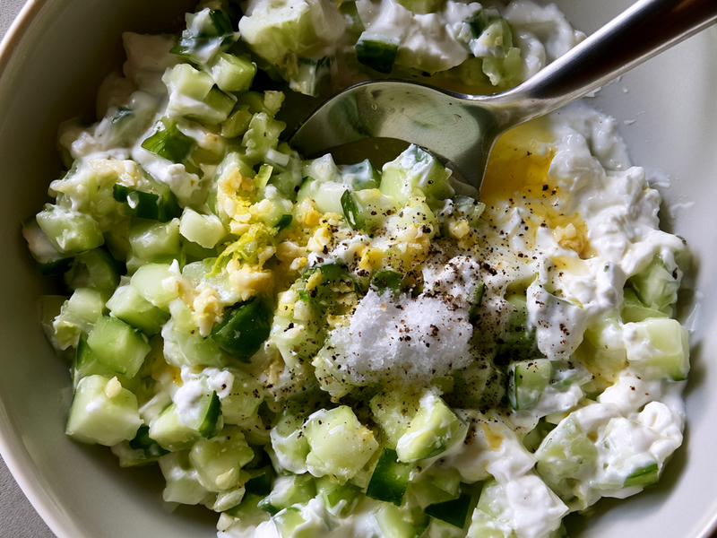 Creamy cucumber yogurt sauce mixed in a bowl with garlic and lemon.