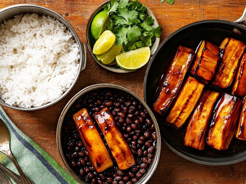 Fluffy white rice, glossy black beans and caramelized plantains served family-style with cilantro and lime