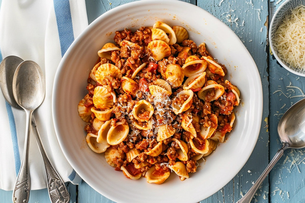 Weeknight bolognese sauce over pasta topped with parmesan and basil