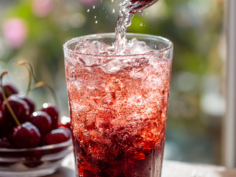 Topping the Sleepy Girl Mocktail with sparkling water to create a fizzy cherry spritz