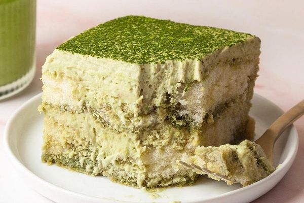 Matcha tiramisu in a dish with matcha powder dusted on top and visible creamy layers