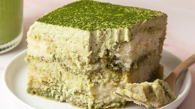 Matcha tiramisu in a dish with matcha powder dusted on top and visible creamy layers