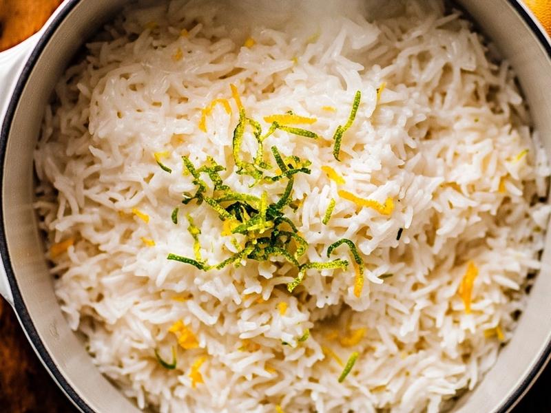 Coconut rice simmering with lime zest in a small saucepan