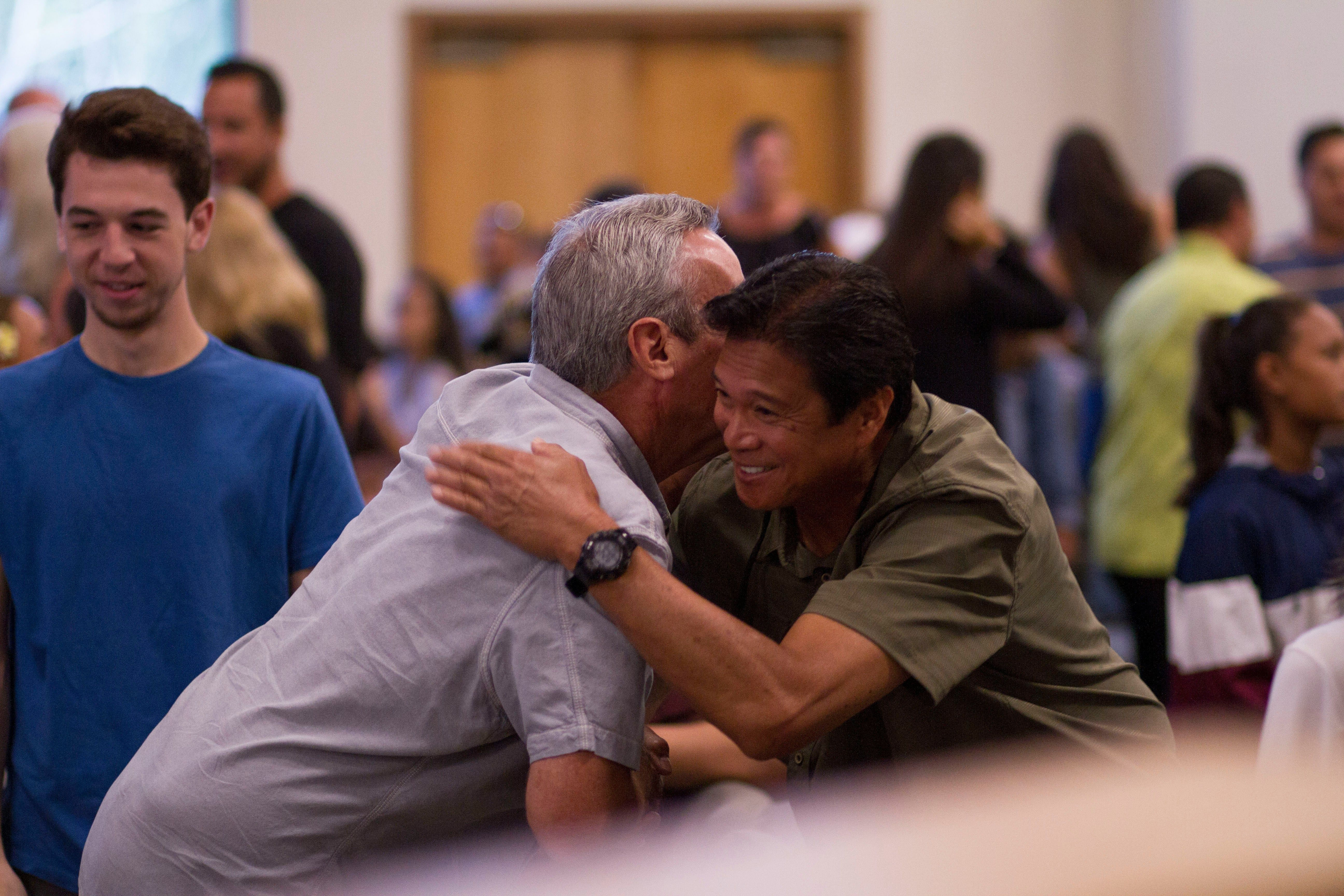 Two men embracing in a community center
