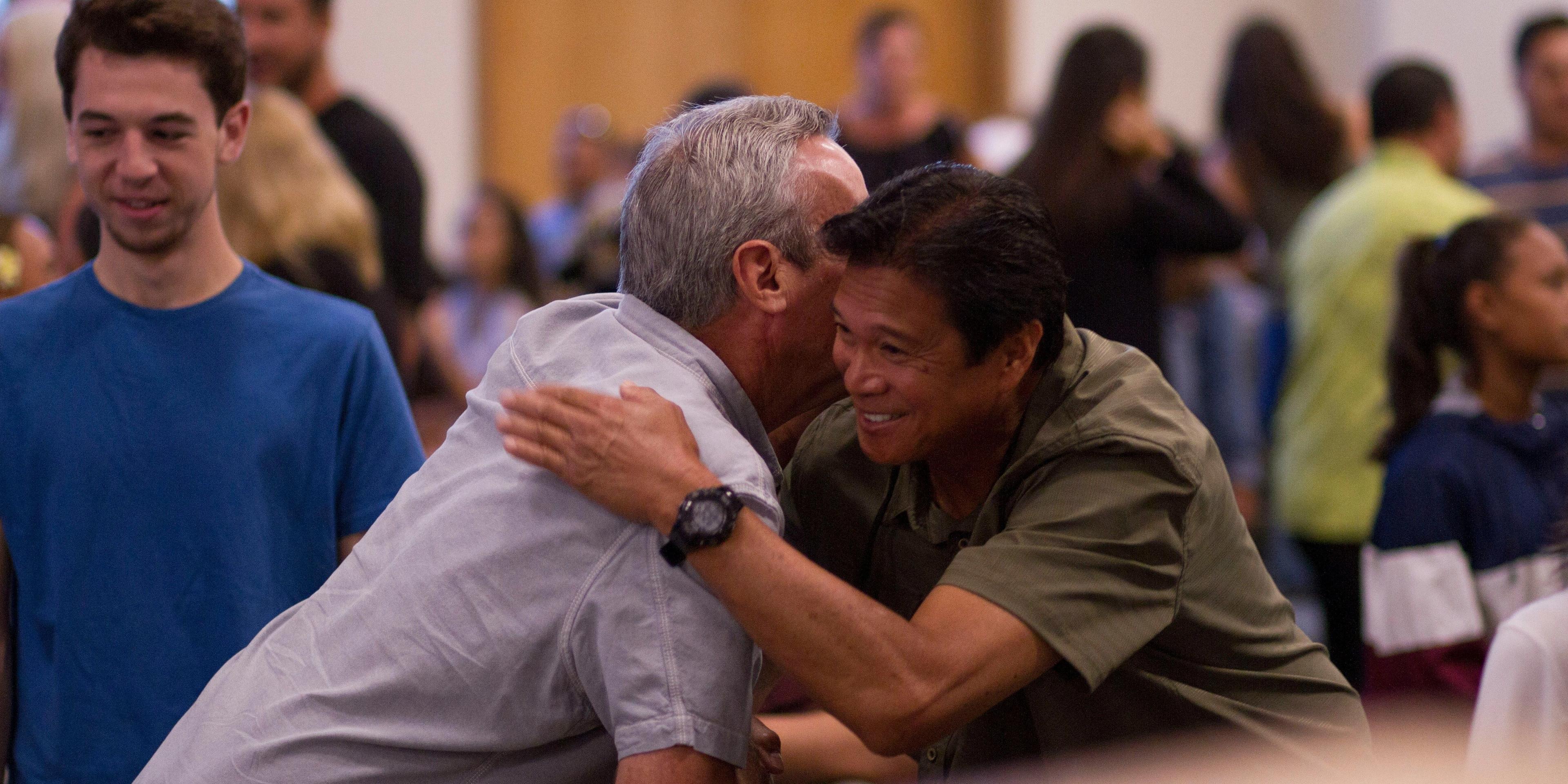 Two men embracing in a community center