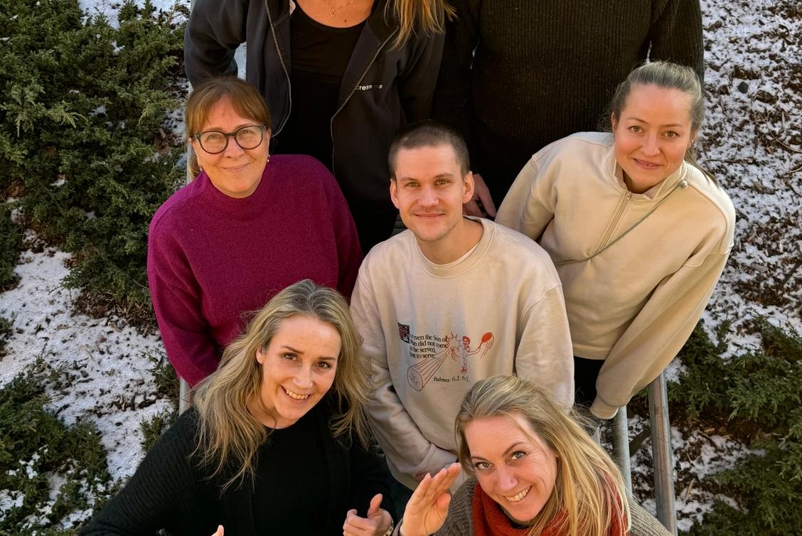 Bilde av 7 glade mennesker i en trapp.