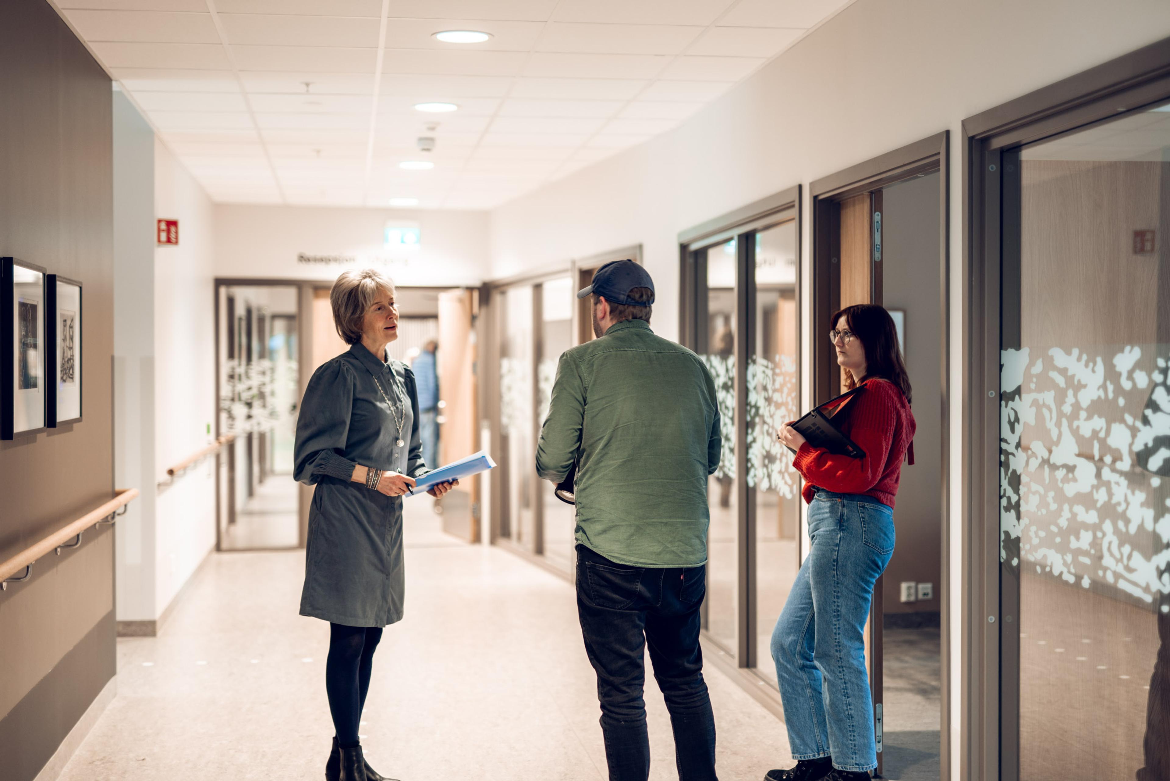 Bilde av tre mennesker i en kontorgang.