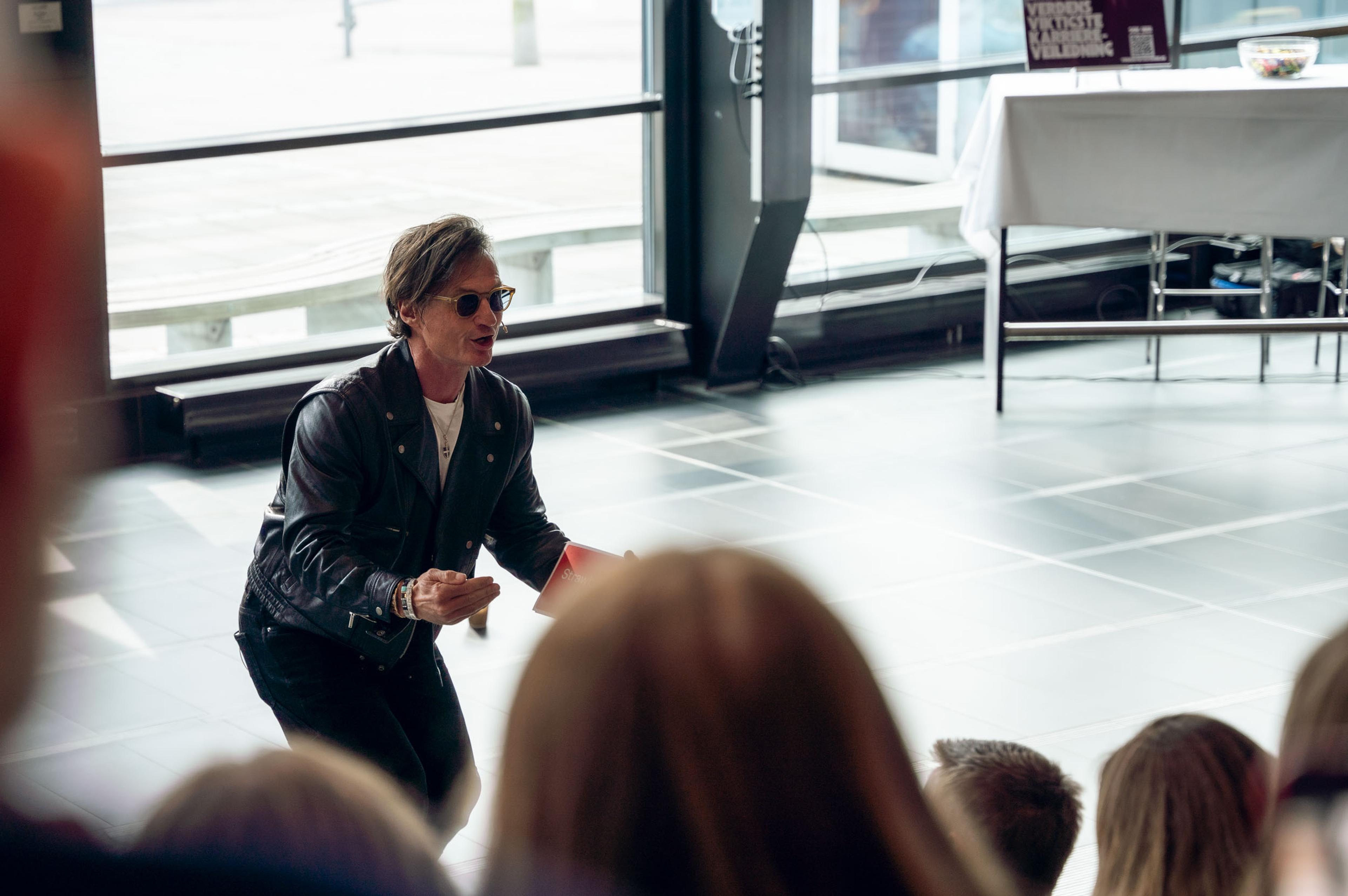 Bilde av Petter Stordalen snakker foran en sal med publikum.