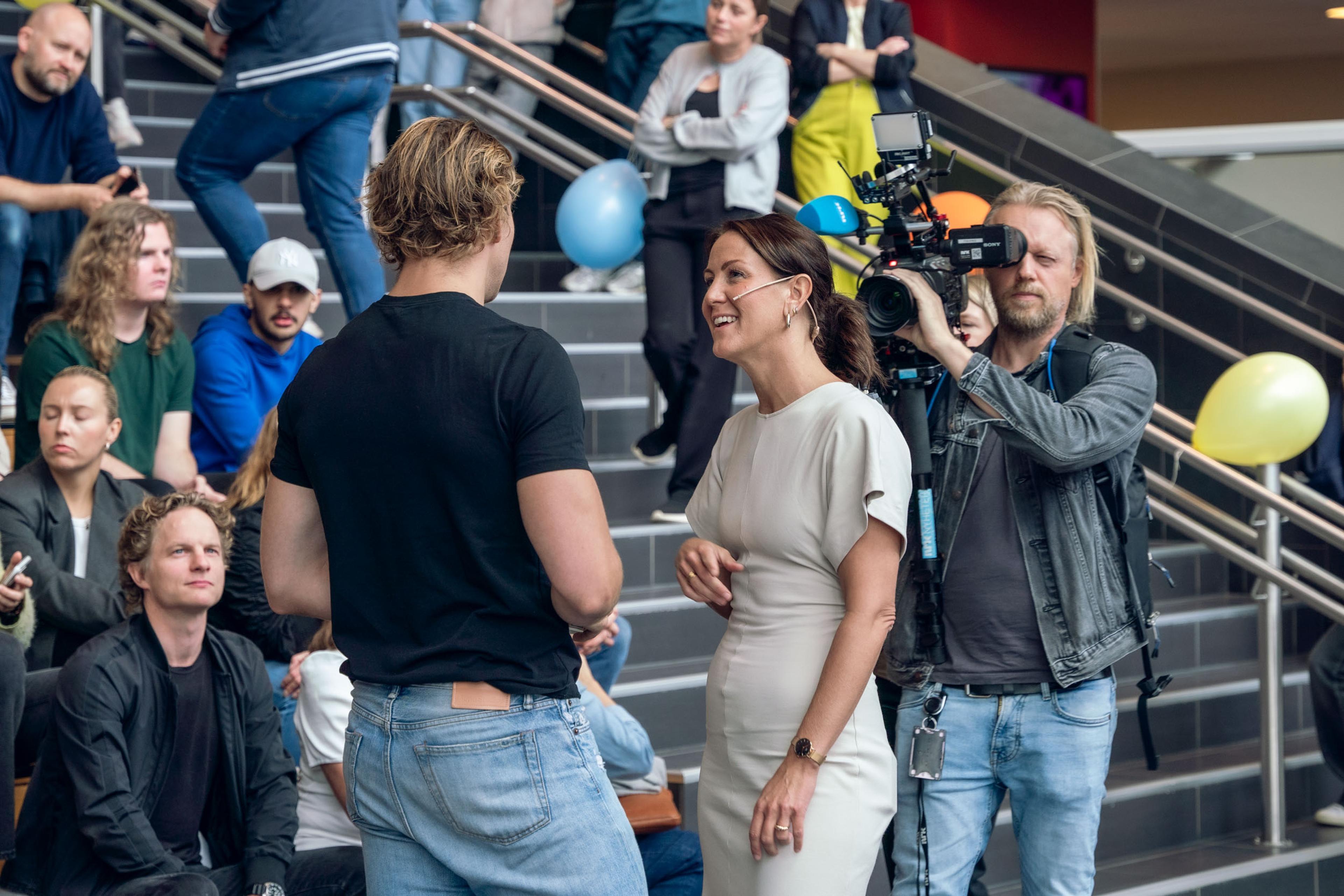 Bilde av Oscar Westerlin og Tonje Brenna i samtale, mens en mann filmer de.