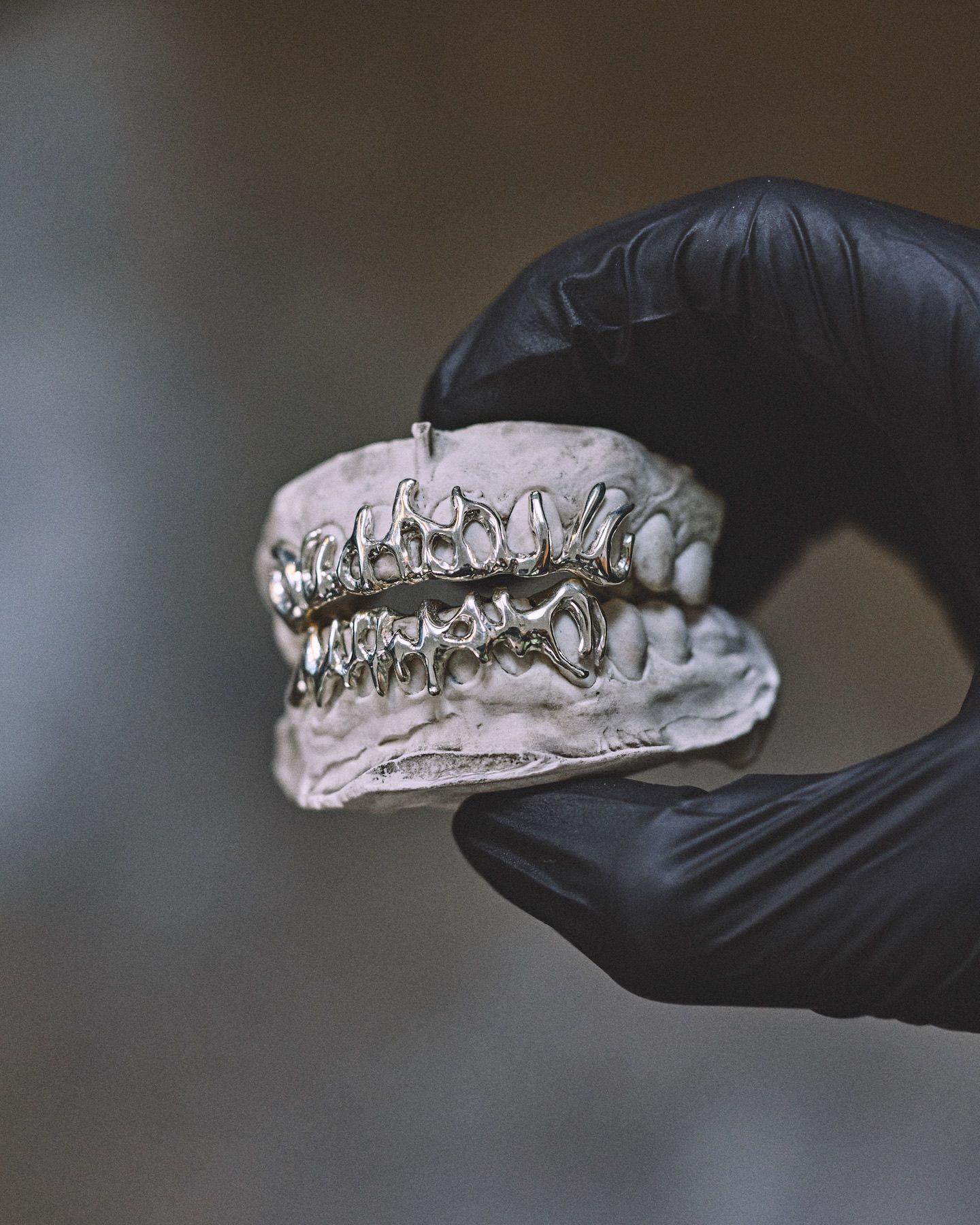 Grillz en argent à motif de lettrage tenu en main gantée