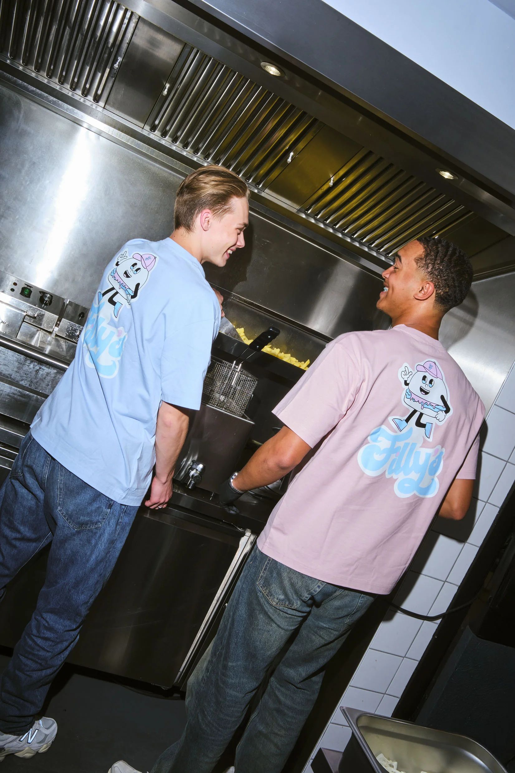 Twee medewerkers in de keuken, mascotte op de rug