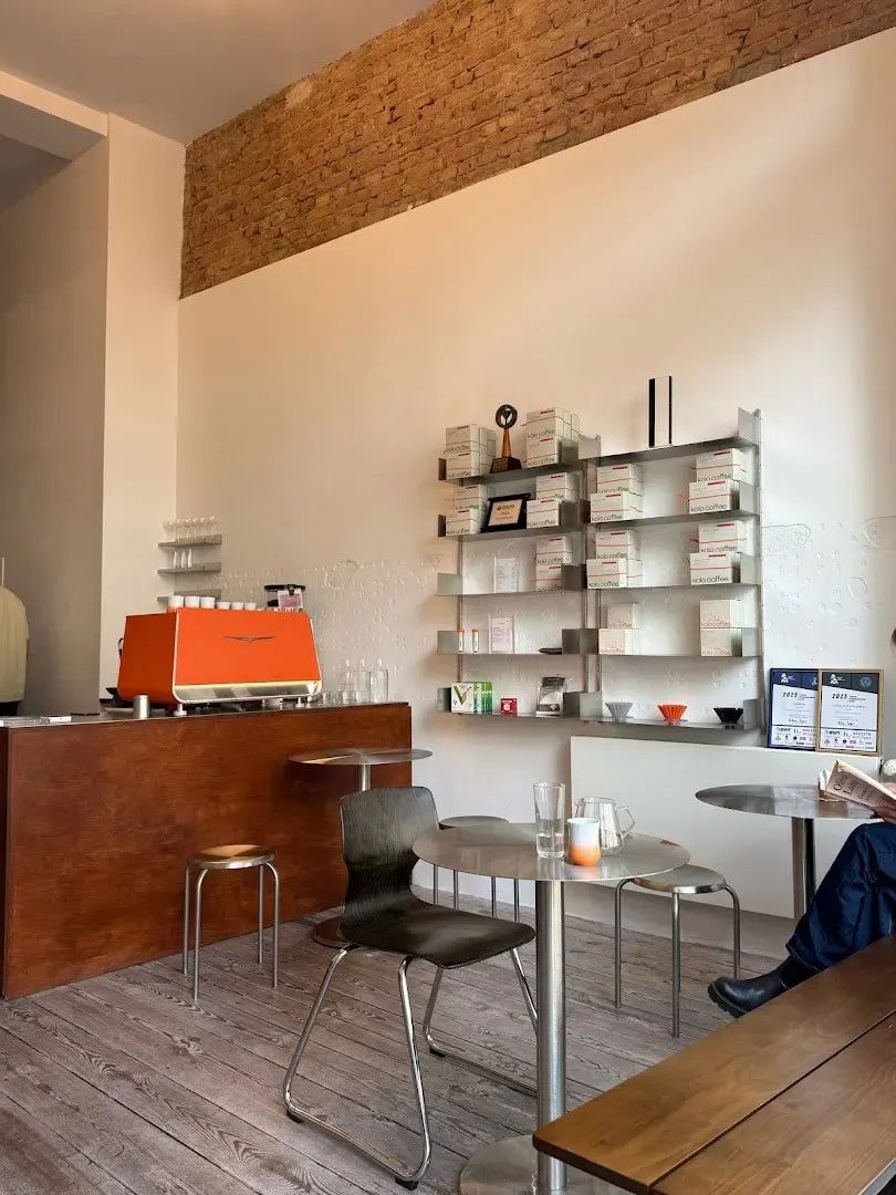 Innenraum von Kolo Coffee: orangefarbene Espressomaschine auf dem Holztresen