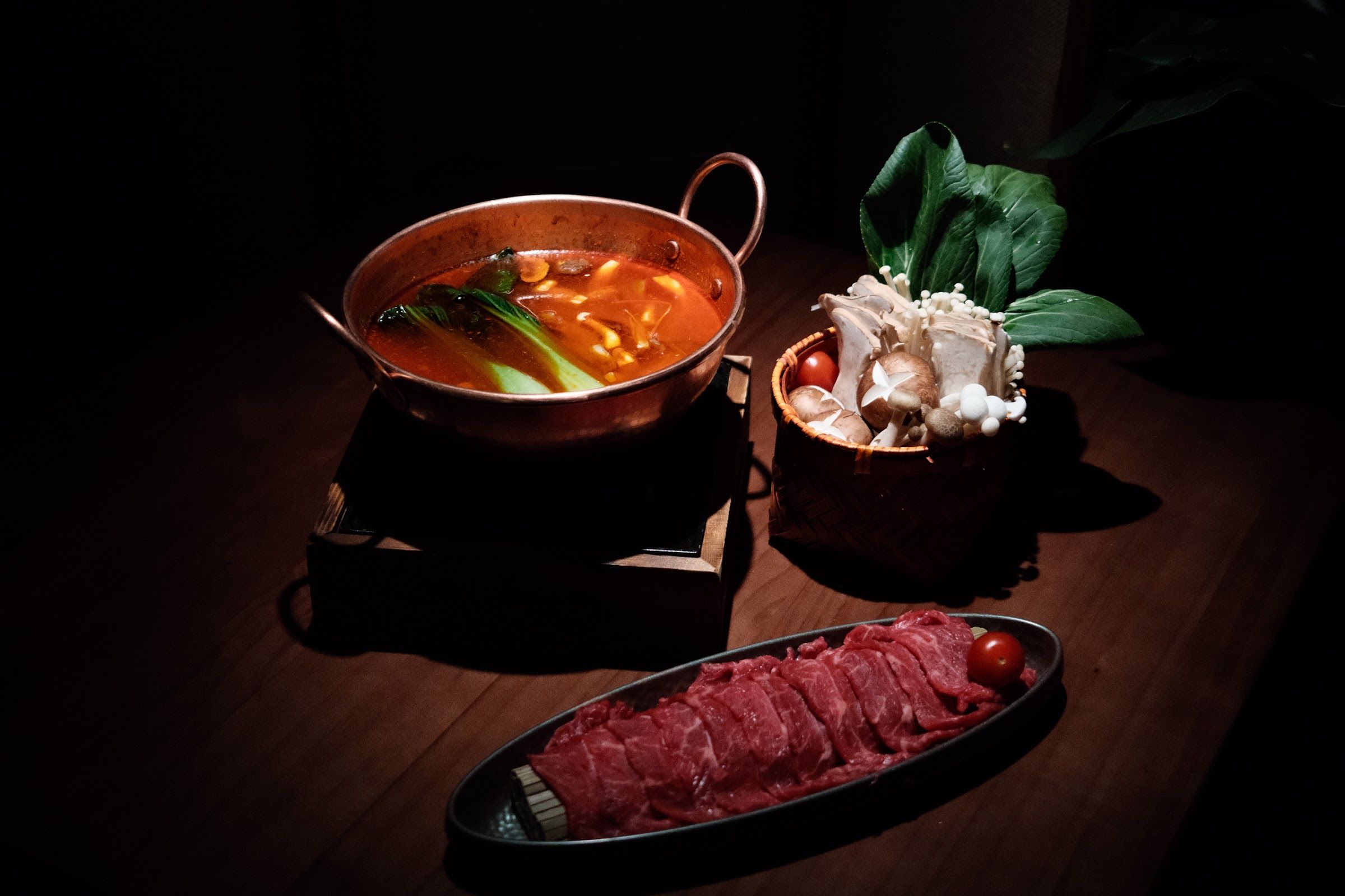 Copper pot with broth, raw beef, mushrooms and pak choi at FúFú Bistro