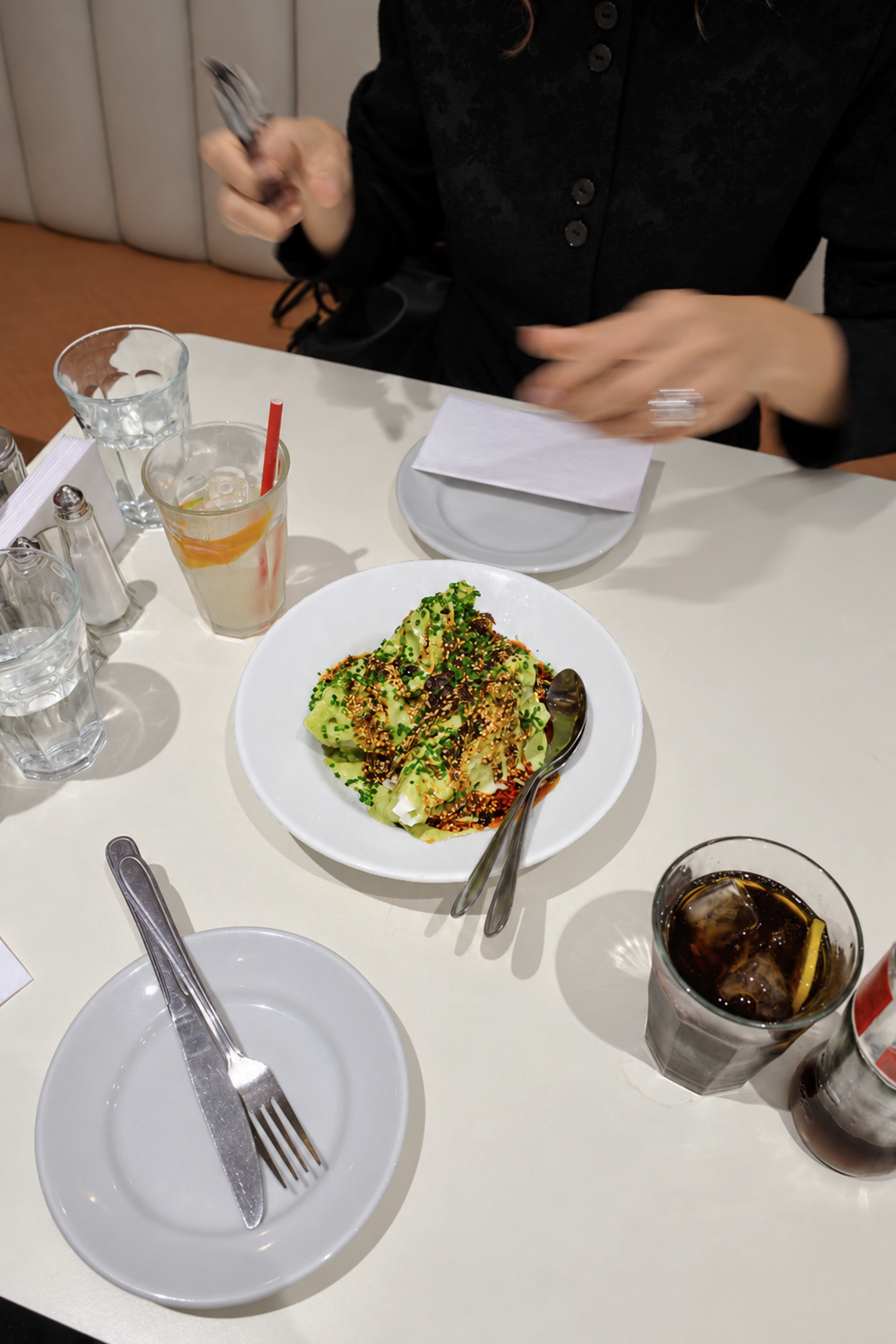 Spicy Green Goddess: Eisbergsalat mit grünem Kräuterdressing, Crispy Chili und Schnittlauch in einer weißen Schale, daneben ein Löffel