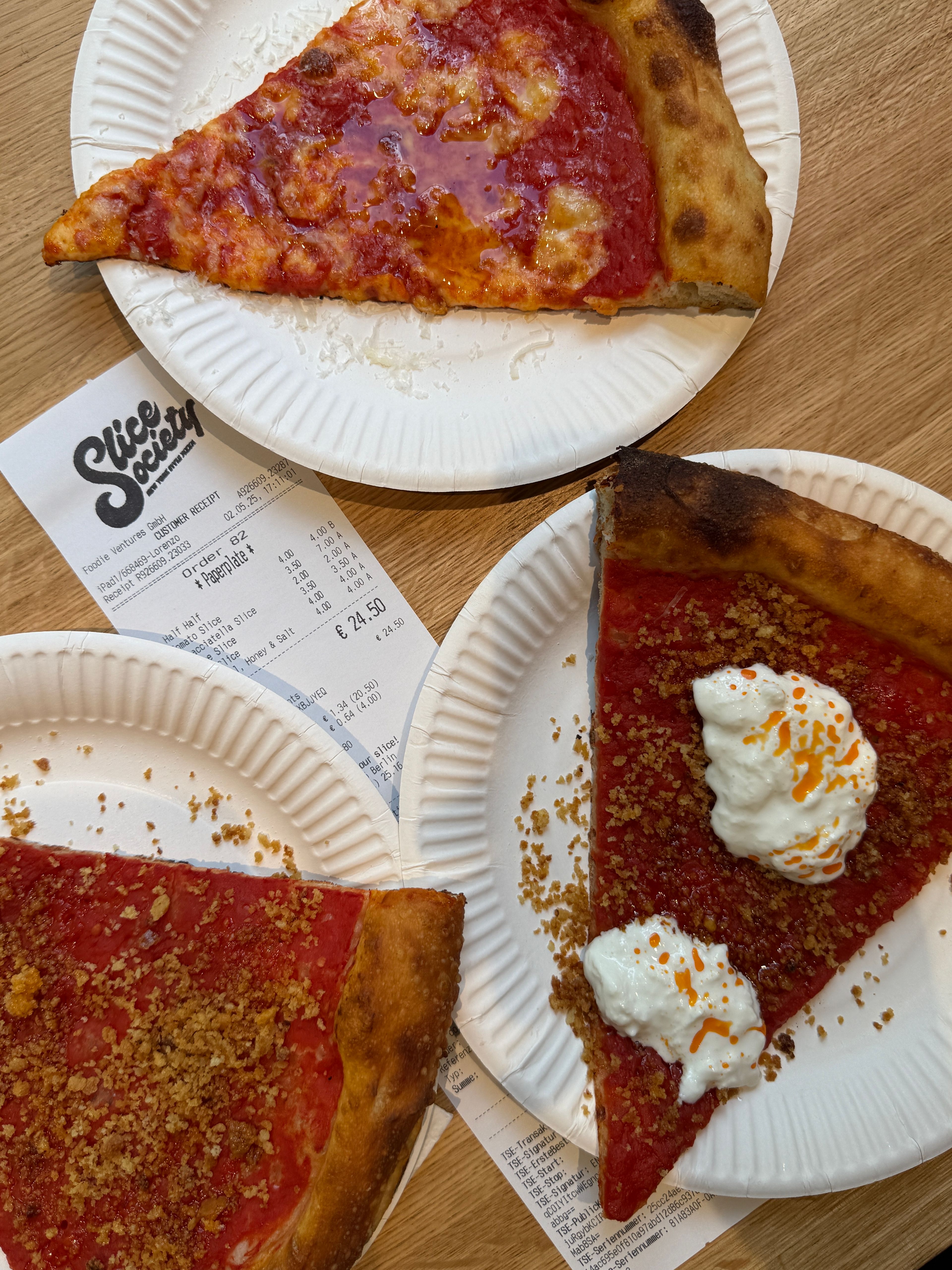 Pizza slices on paper plates at Slice Society, with the receipt