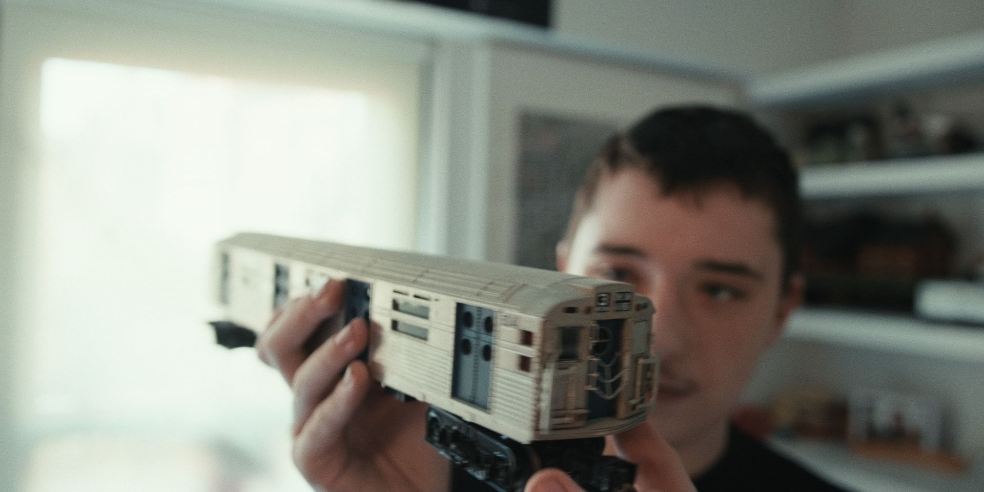 A boy holds up a model subway car.
