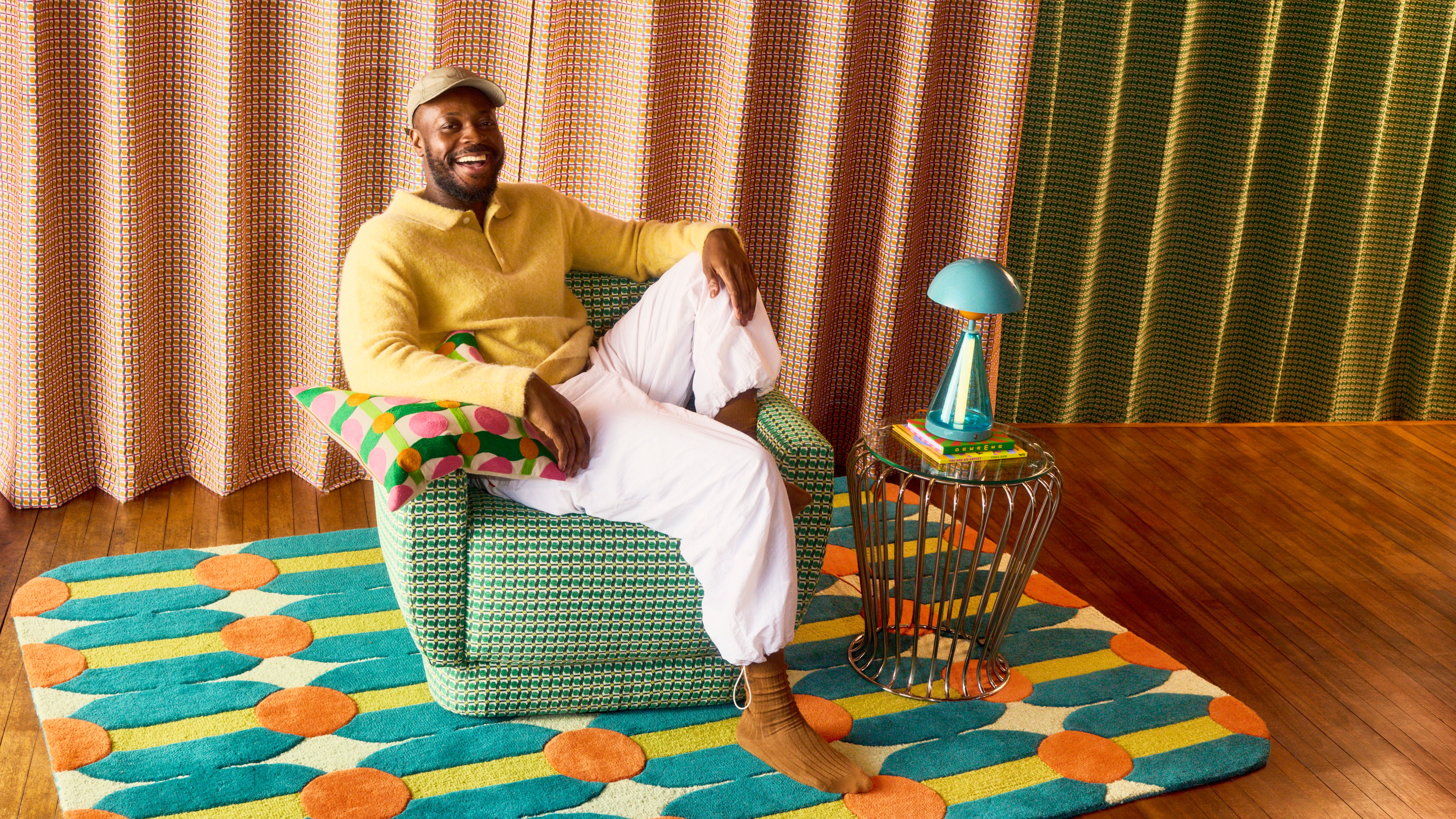 Yinka Ilori sitting on a chair from the collection