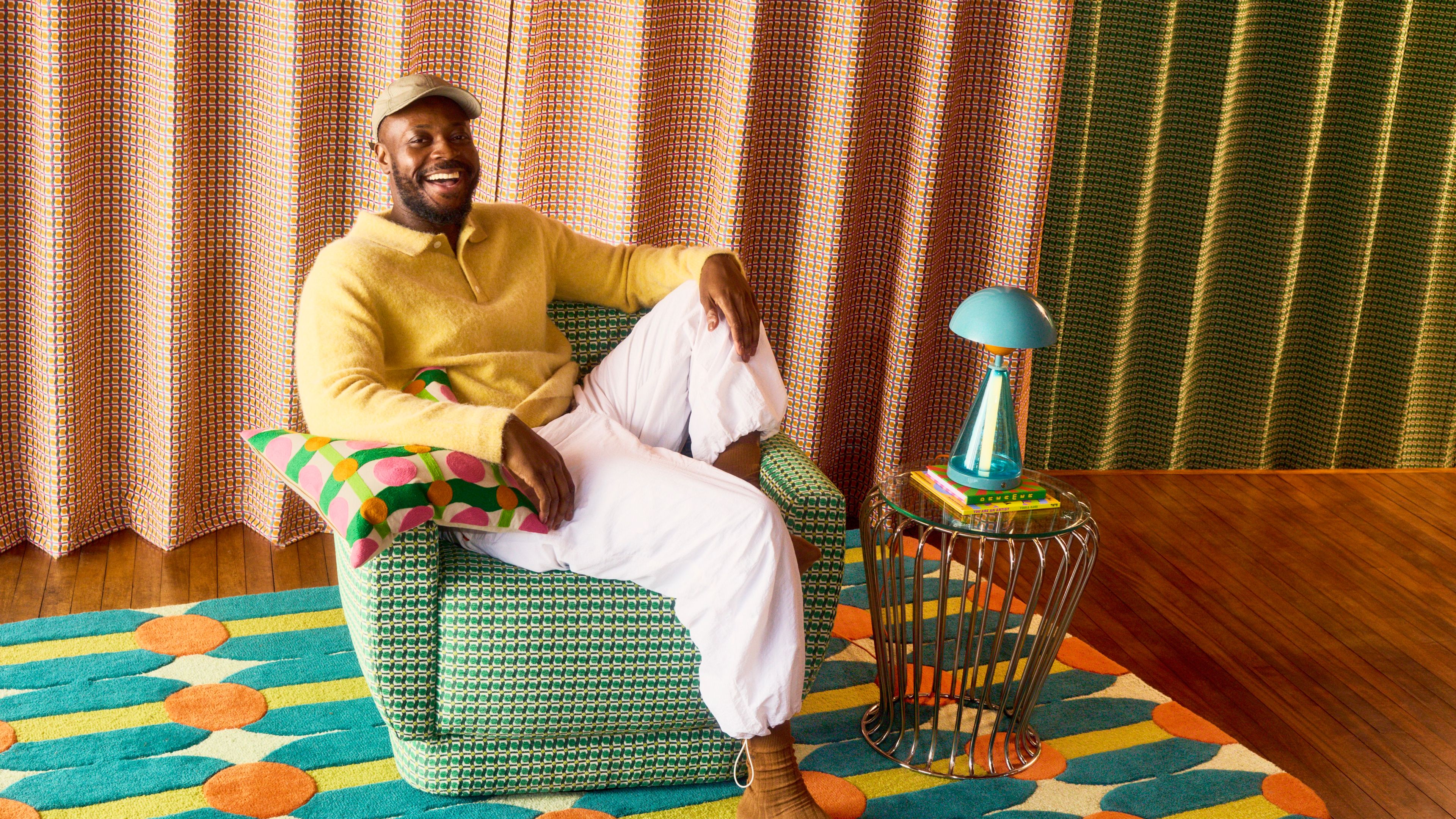 Yinka Ilori sitting on a chair from the collection