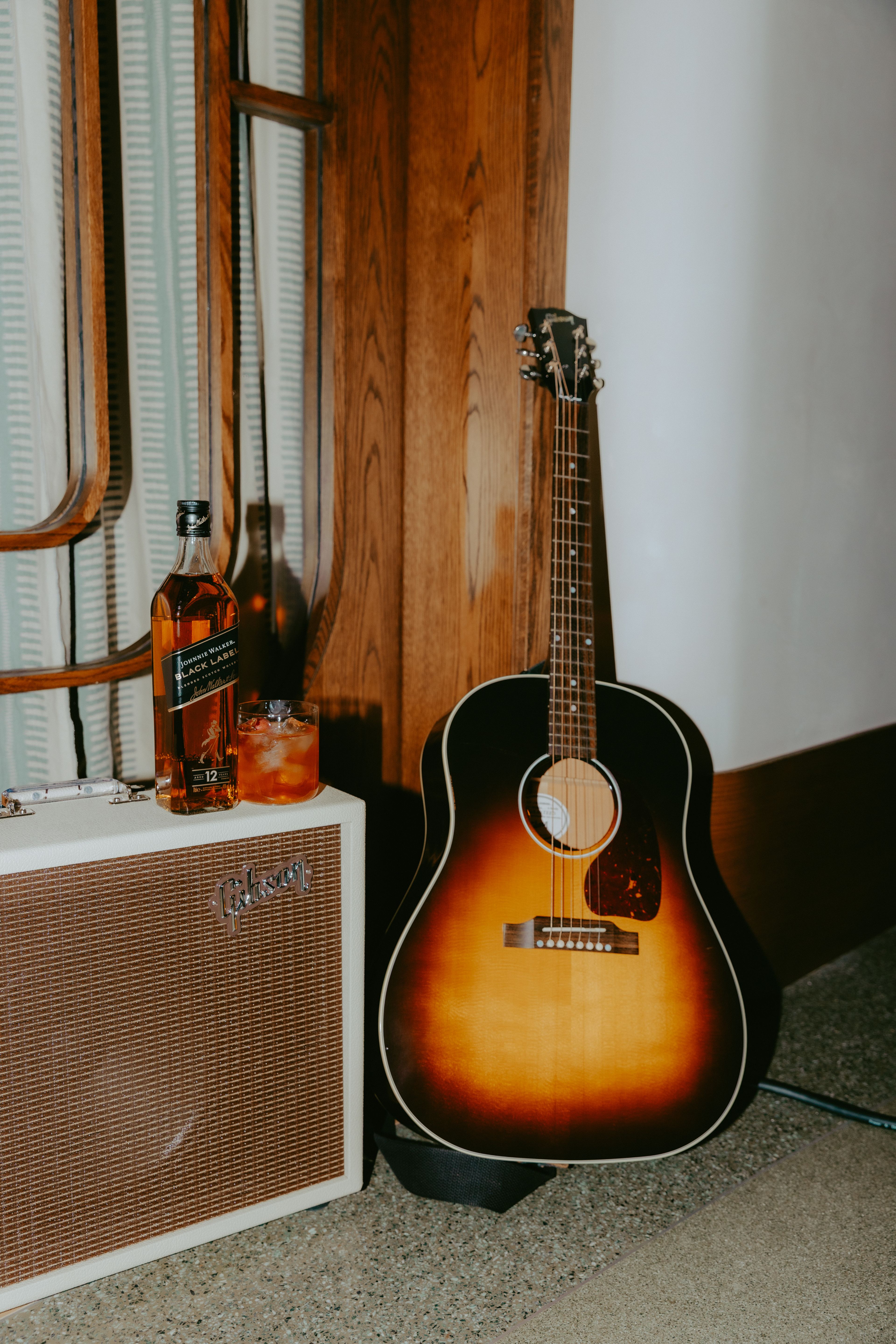 Photo of a johnnie Walker bottle and cocktail on top of a Gibson amp next to a Gibson Guitar