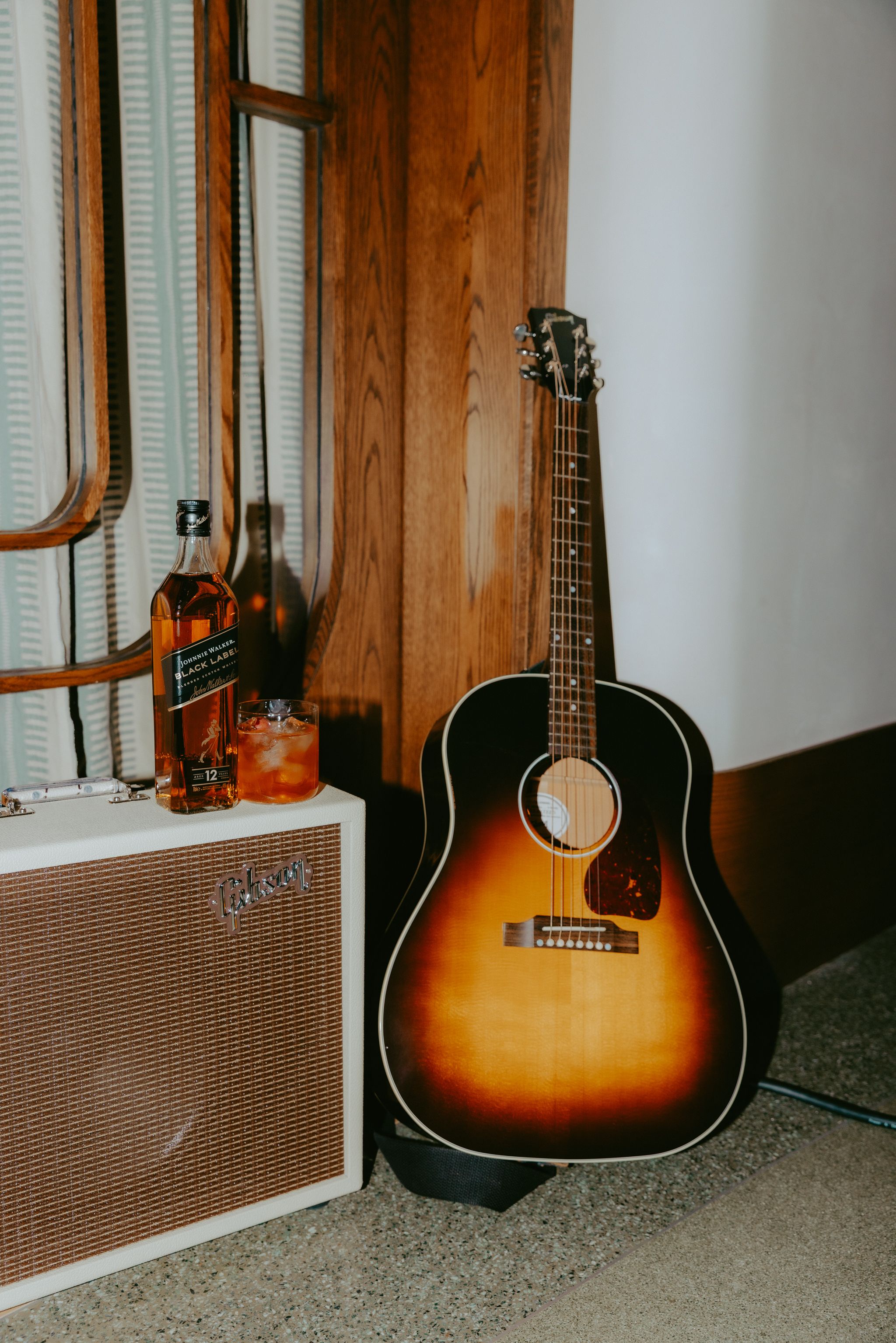 Photo of a johnnie Walker bottle and cocktail on top of a Gibson amp next to a Gibson Guitar
