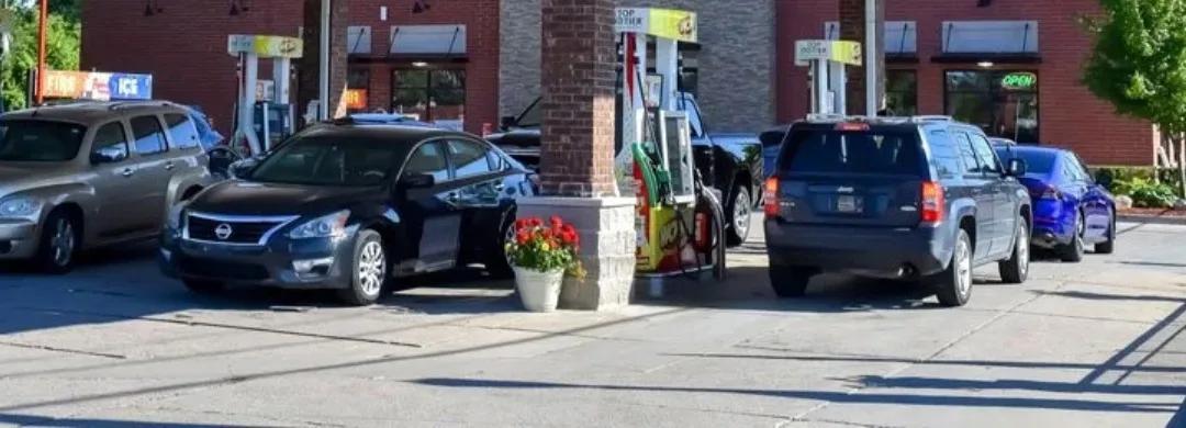 Cars at the pumps of a fuel station beside a brick canopy column