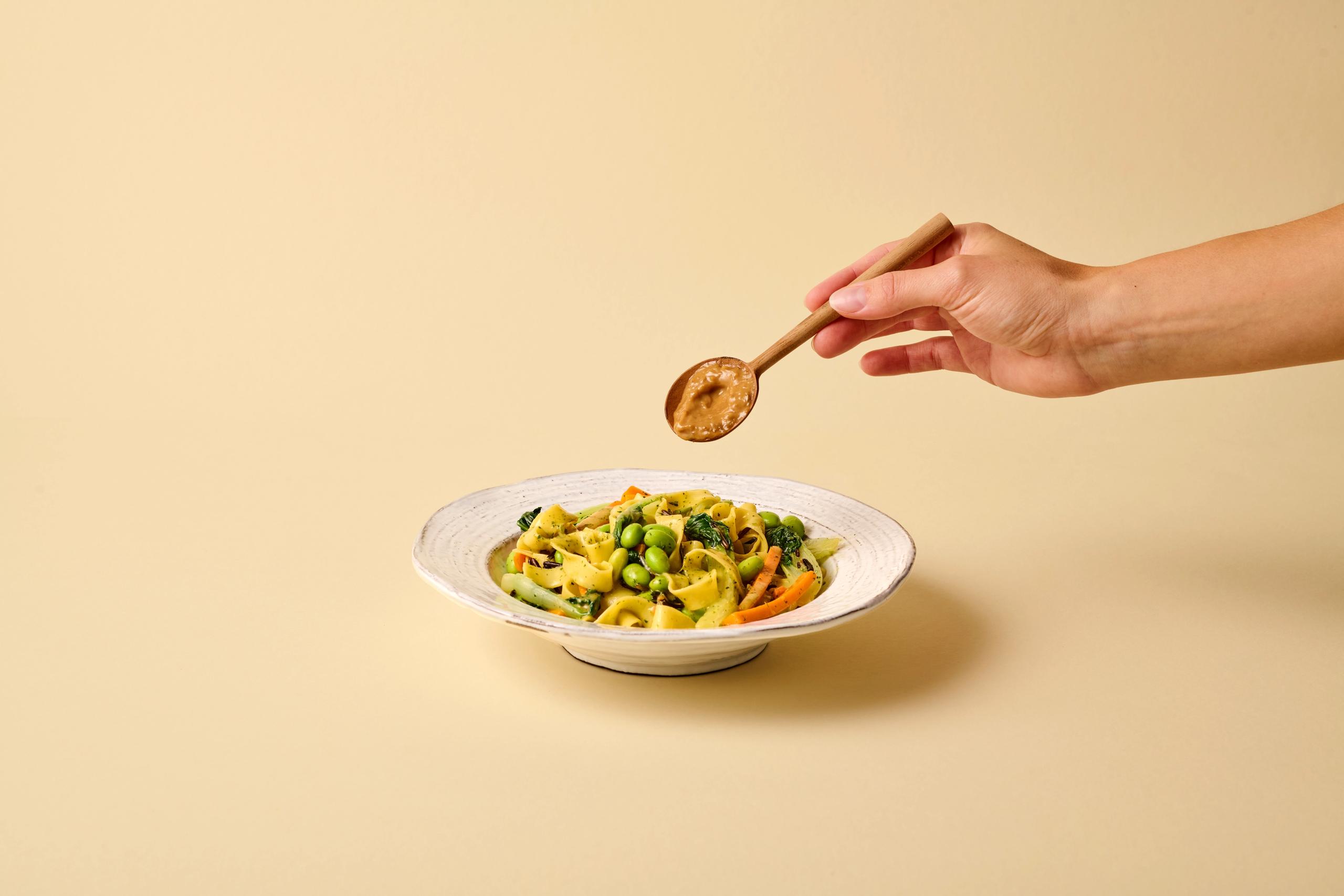 A spoon of miso is added to a dish.
