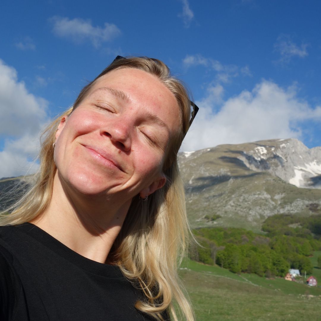 Ronja in front of a mountain panorama.