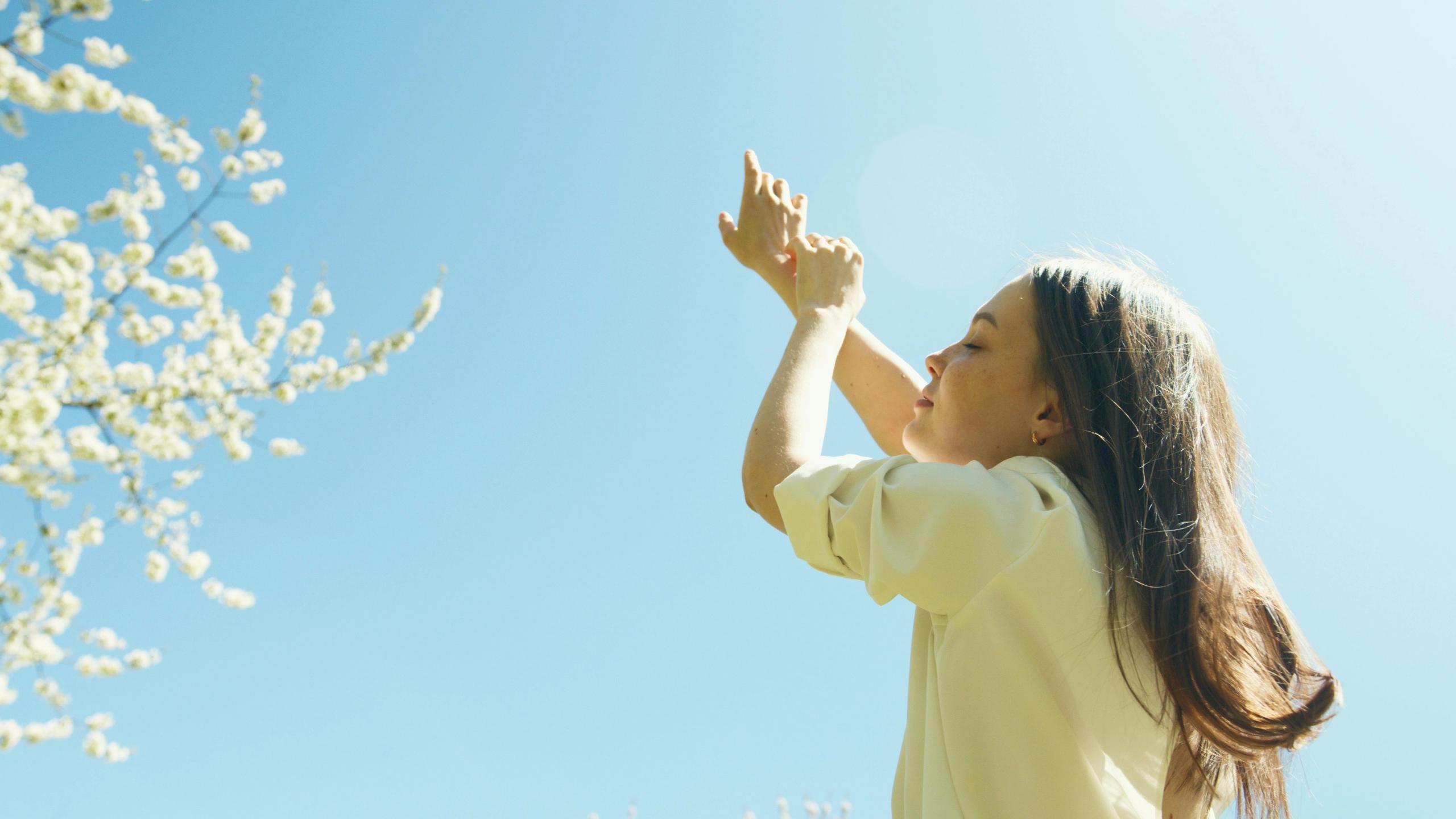 Eine Frau hält ihr Gesicht in die Sonne