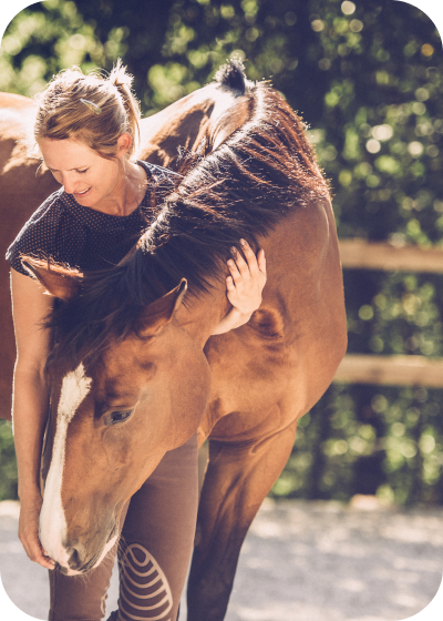 a woman standing next to a brown horse