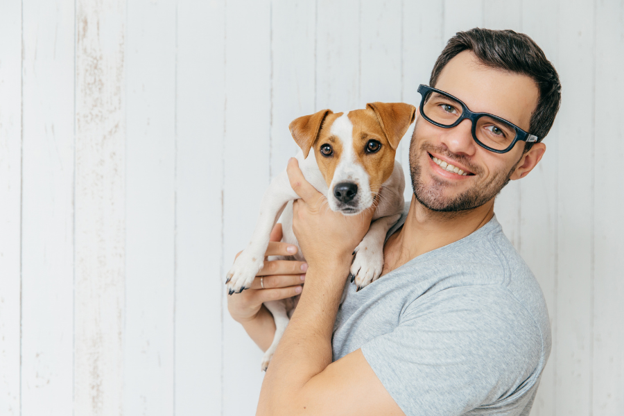 A smiling man in glasses holding a brown and white dog.
