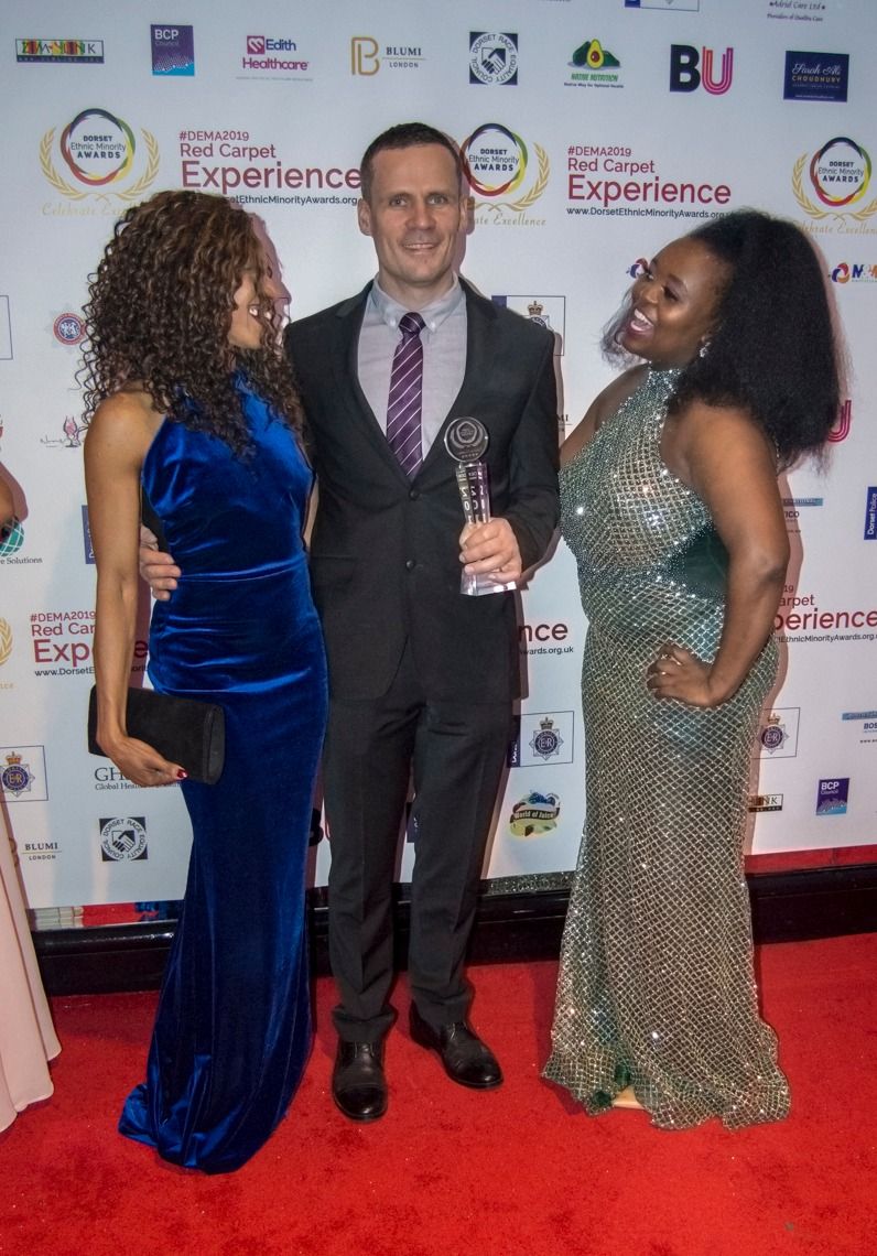 Three guests with a trophy on the red carpet